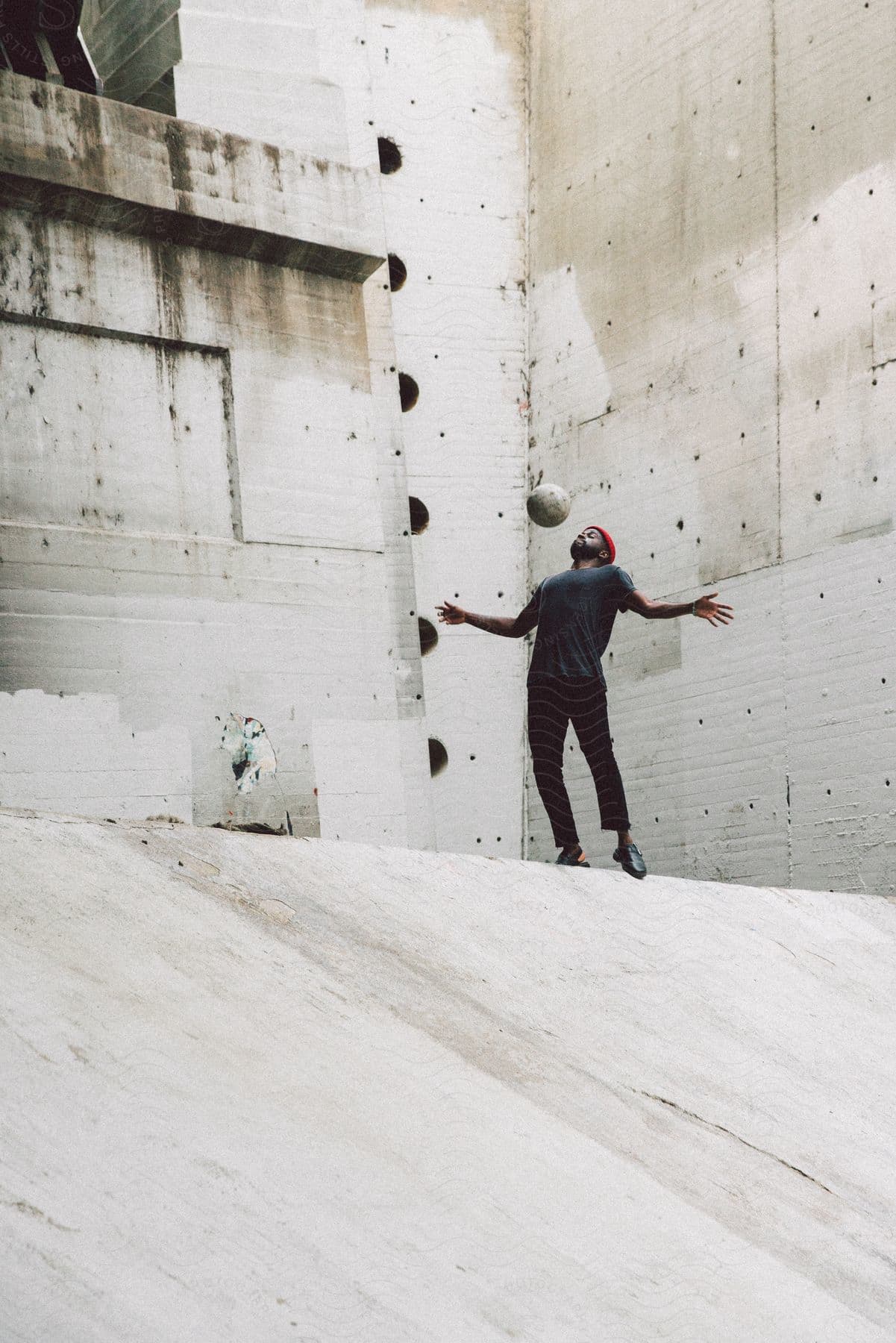 man playing with a soccer ball while standing on concrete pavement