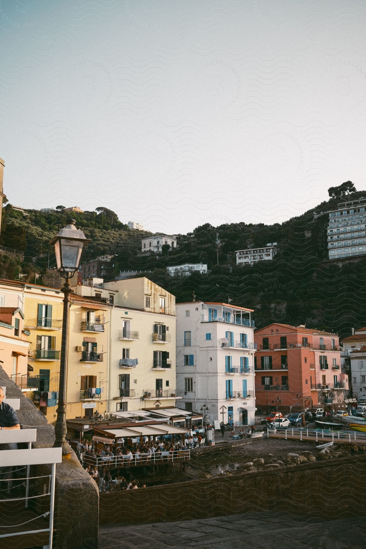 Hillside buildings tower over apartment buildings with crowded patios.