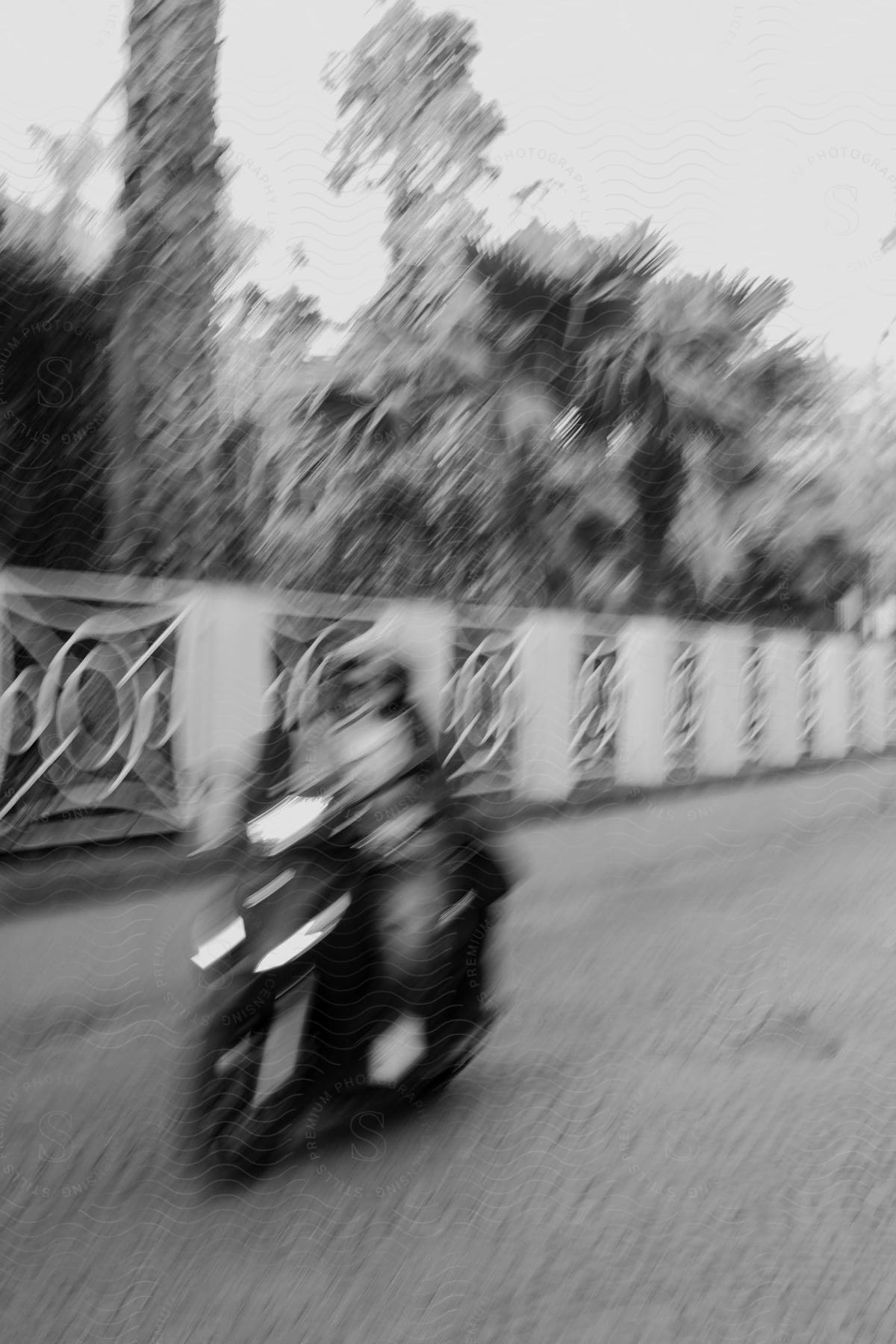 A motorcycle driving down a road with stone pavement, and trees to its side.