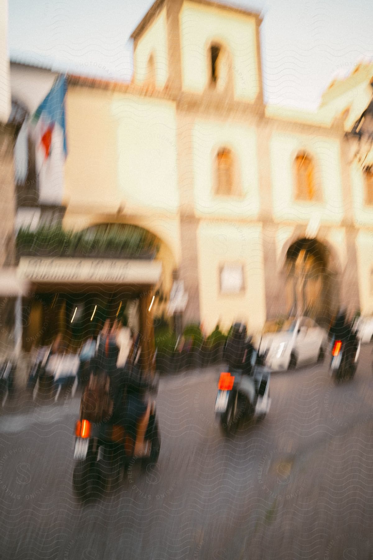 A blurry image of a street scene with motorcycles and a building in the background.