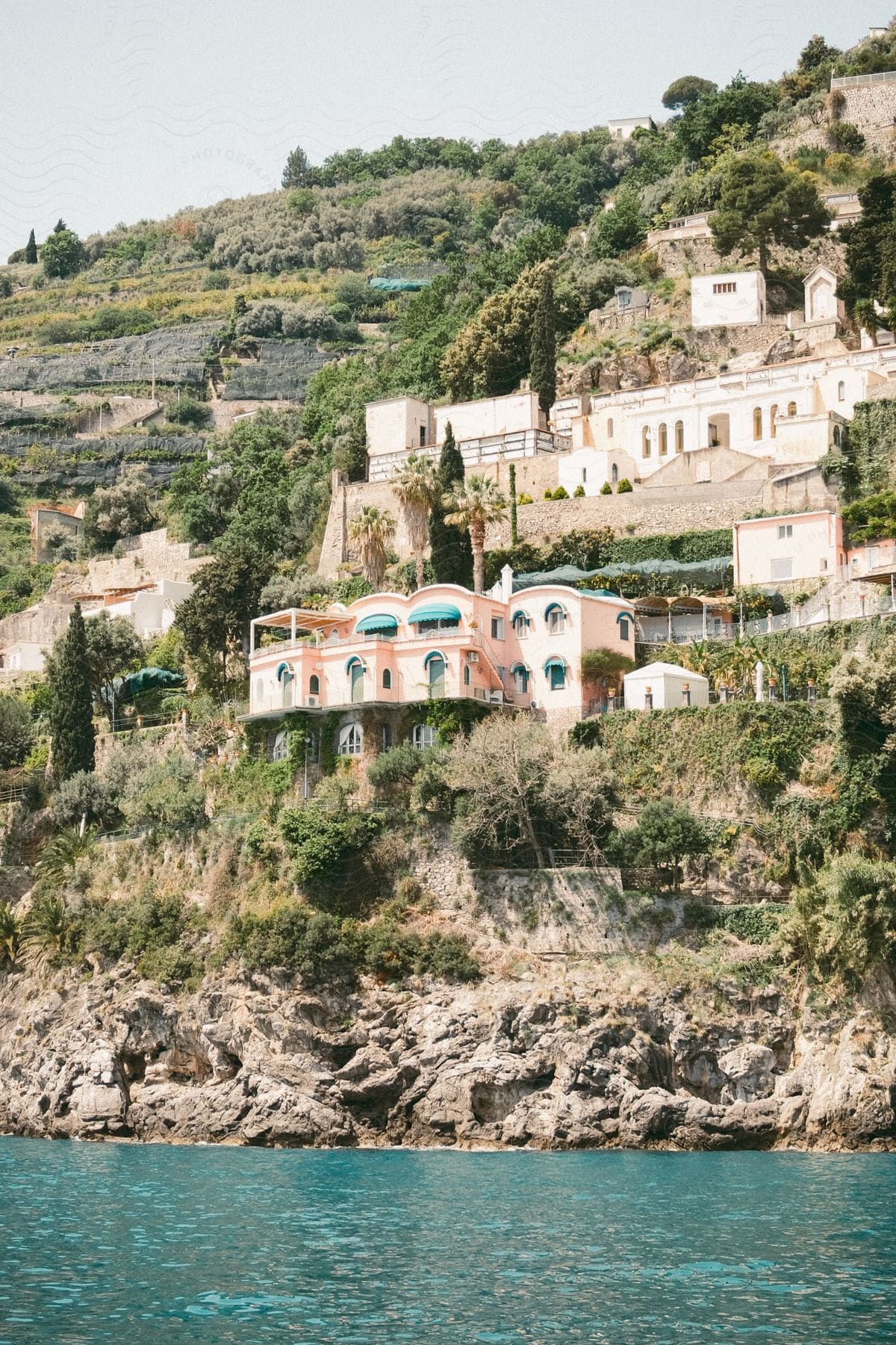 Coastal agricultural fields and buildings occupy mountainside.