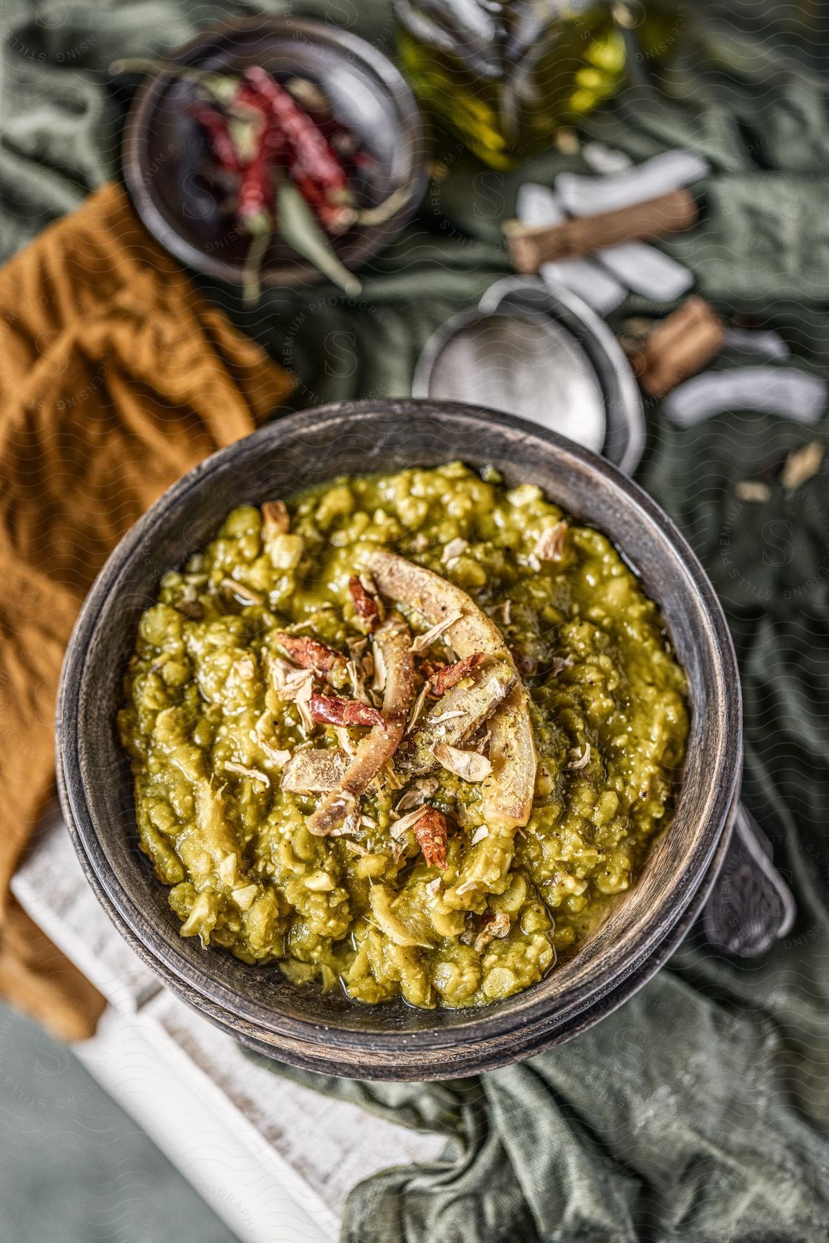 A plate of green risotto with grilled chicken, garnished with red spices.