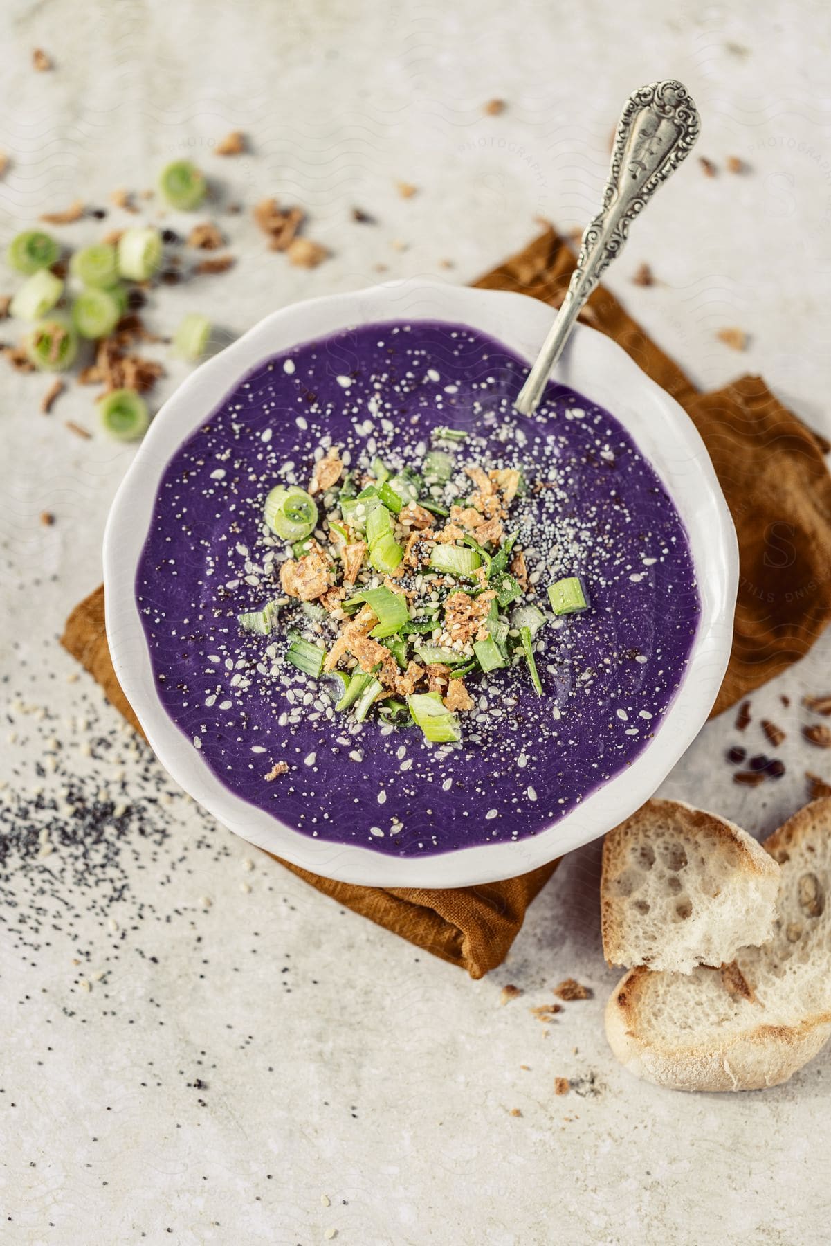 A steaming bowl of purple cabbage soup sits on a table with a side of crusty bread