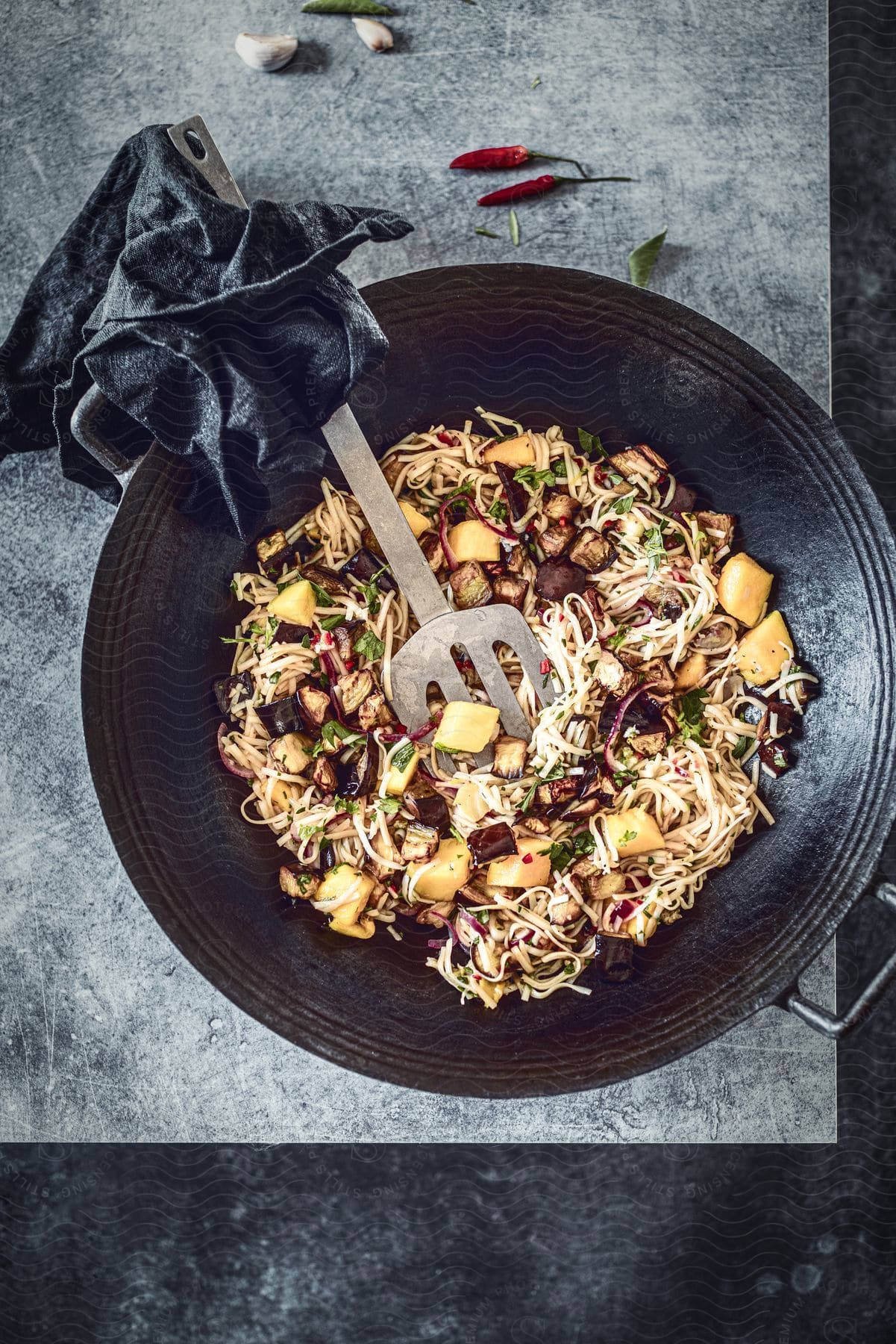 Noodle dish with vegetables and pieces of tofu served in a dark bowl.