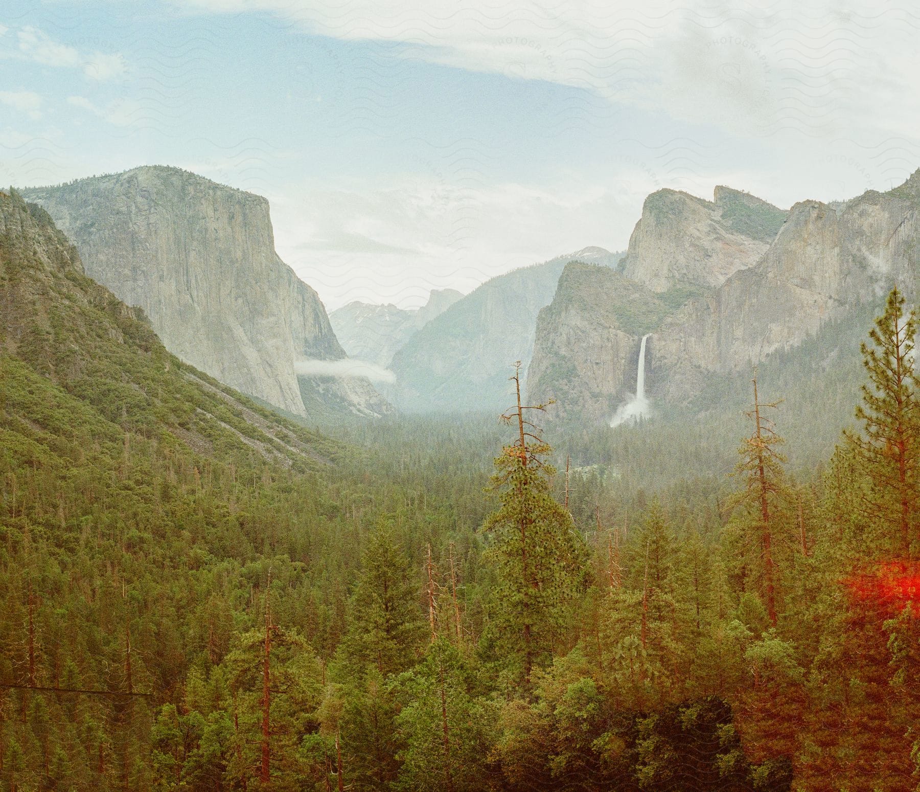 A panoramic view of Yosemite National Park with El Capitan on the left and Bridal Veil Falls on the right.