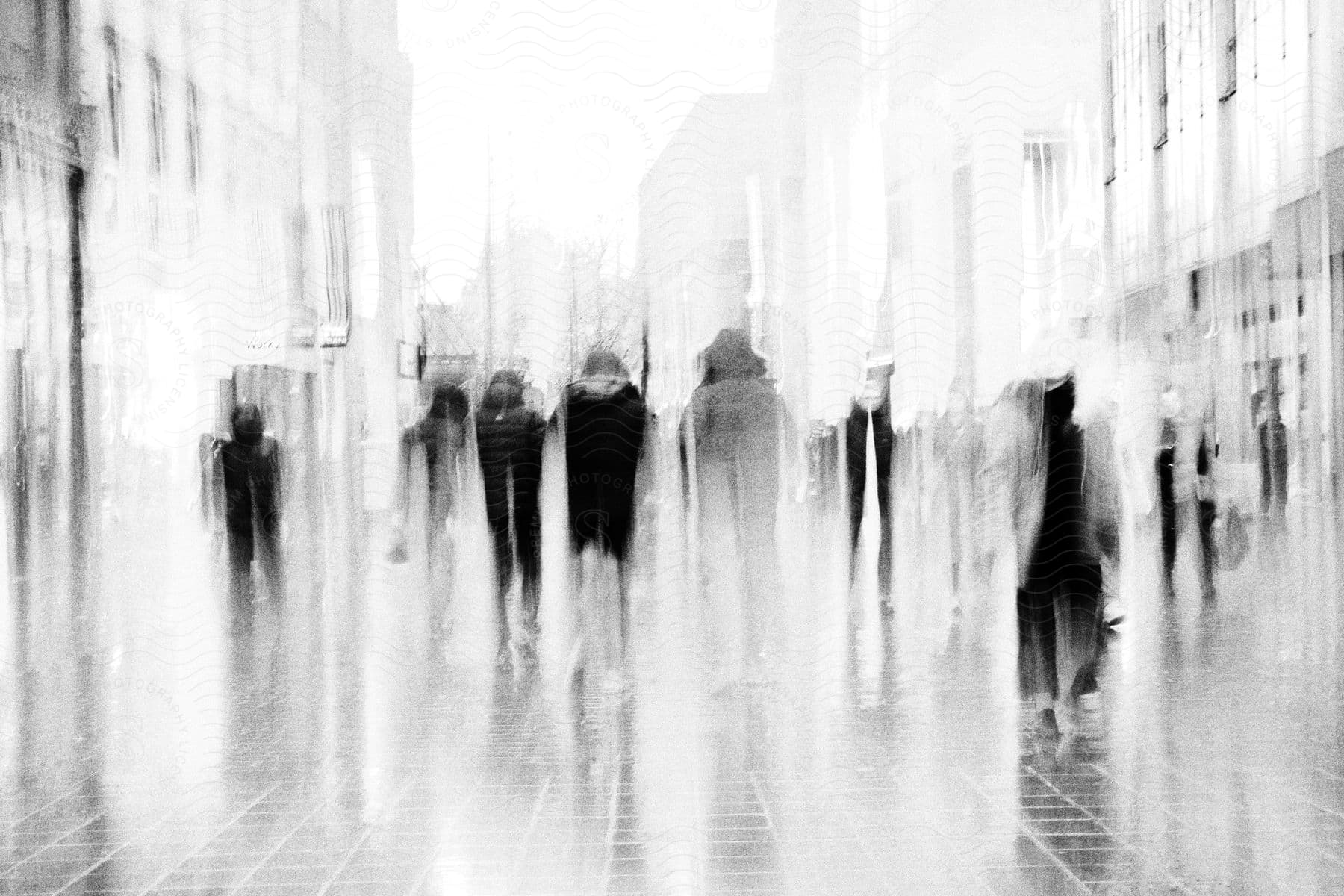 people holding umbrellas as they walk down a street slick with rain.