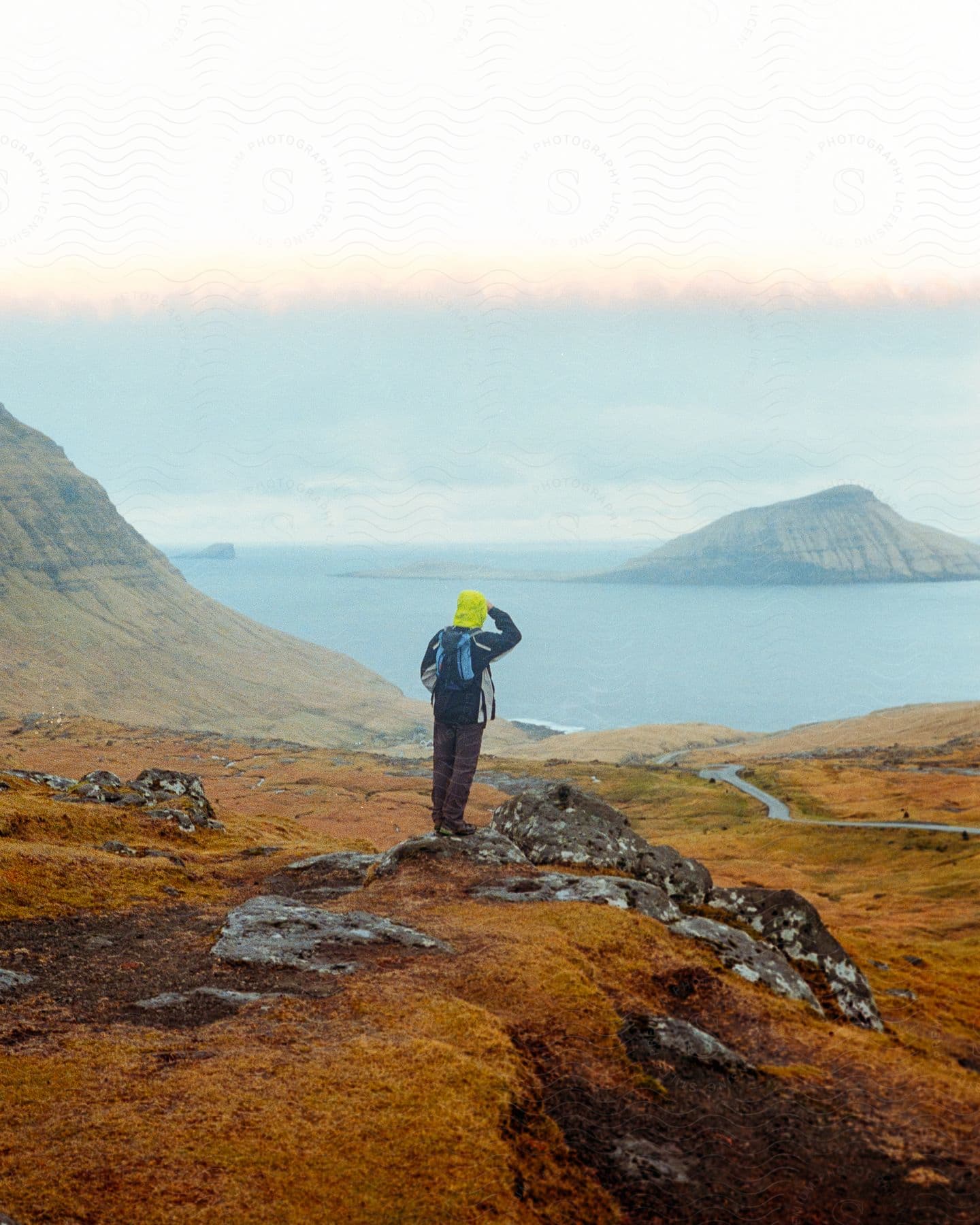 Natural landscape with a man's back overlooking the ocean against a morning sky