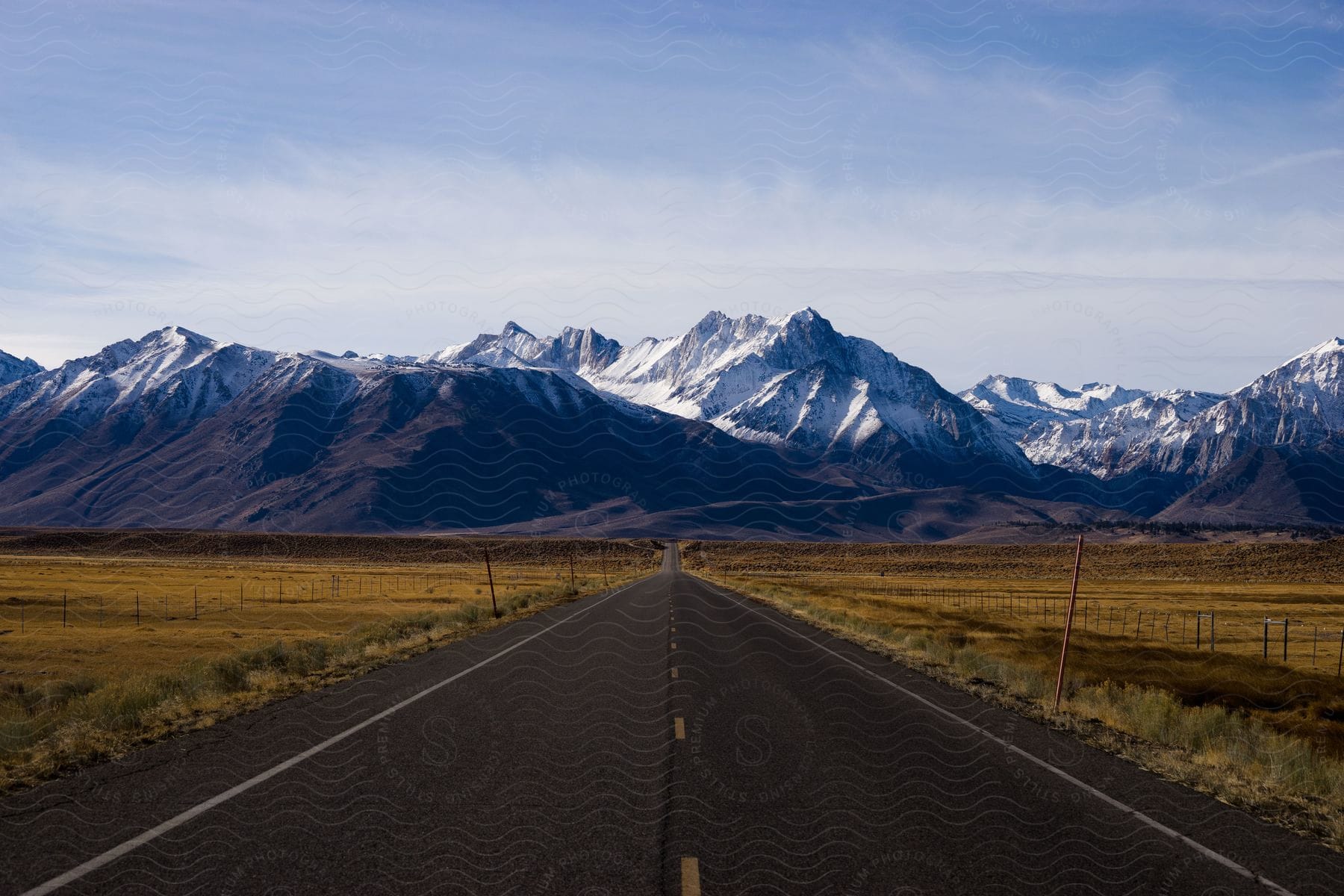 A road running past agricultural fields towards a mountain range