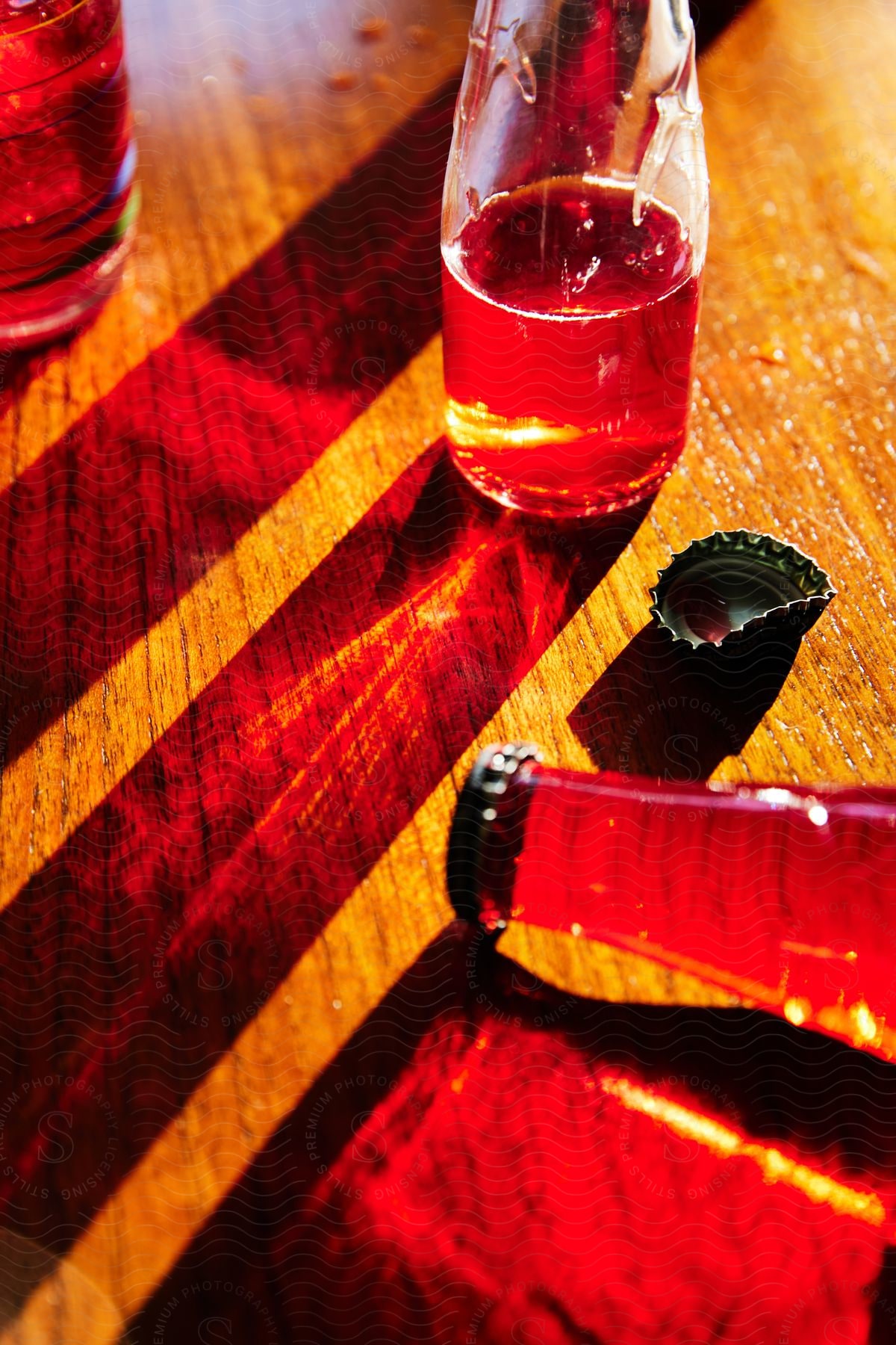 a red bottle with a black cap and a half bottle sitting on a light-colored wooden table.