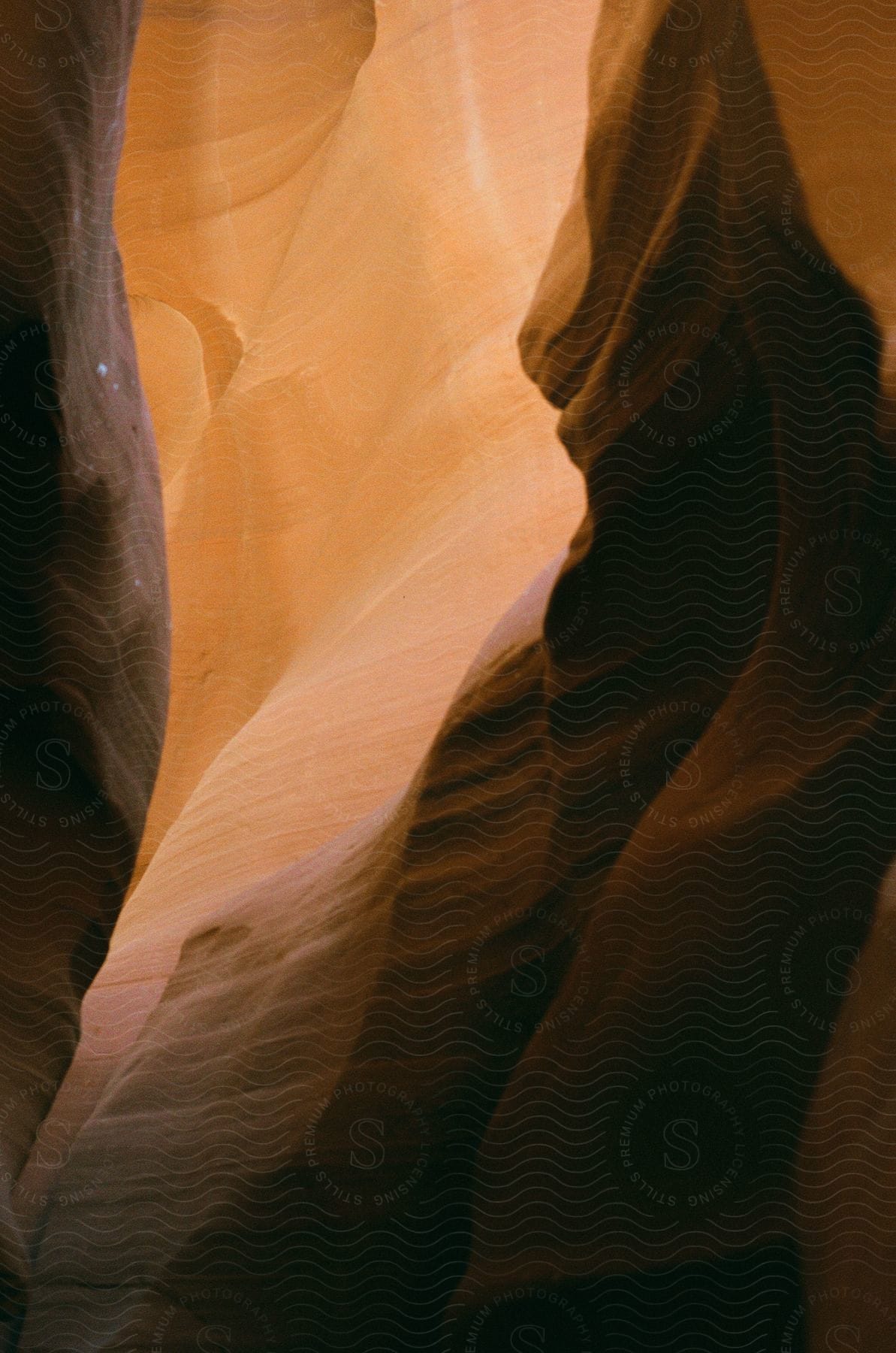 Sunlight streams through the narrow opening of Antelope Canyon, illuminating the canyon walls in shades of orange and red.