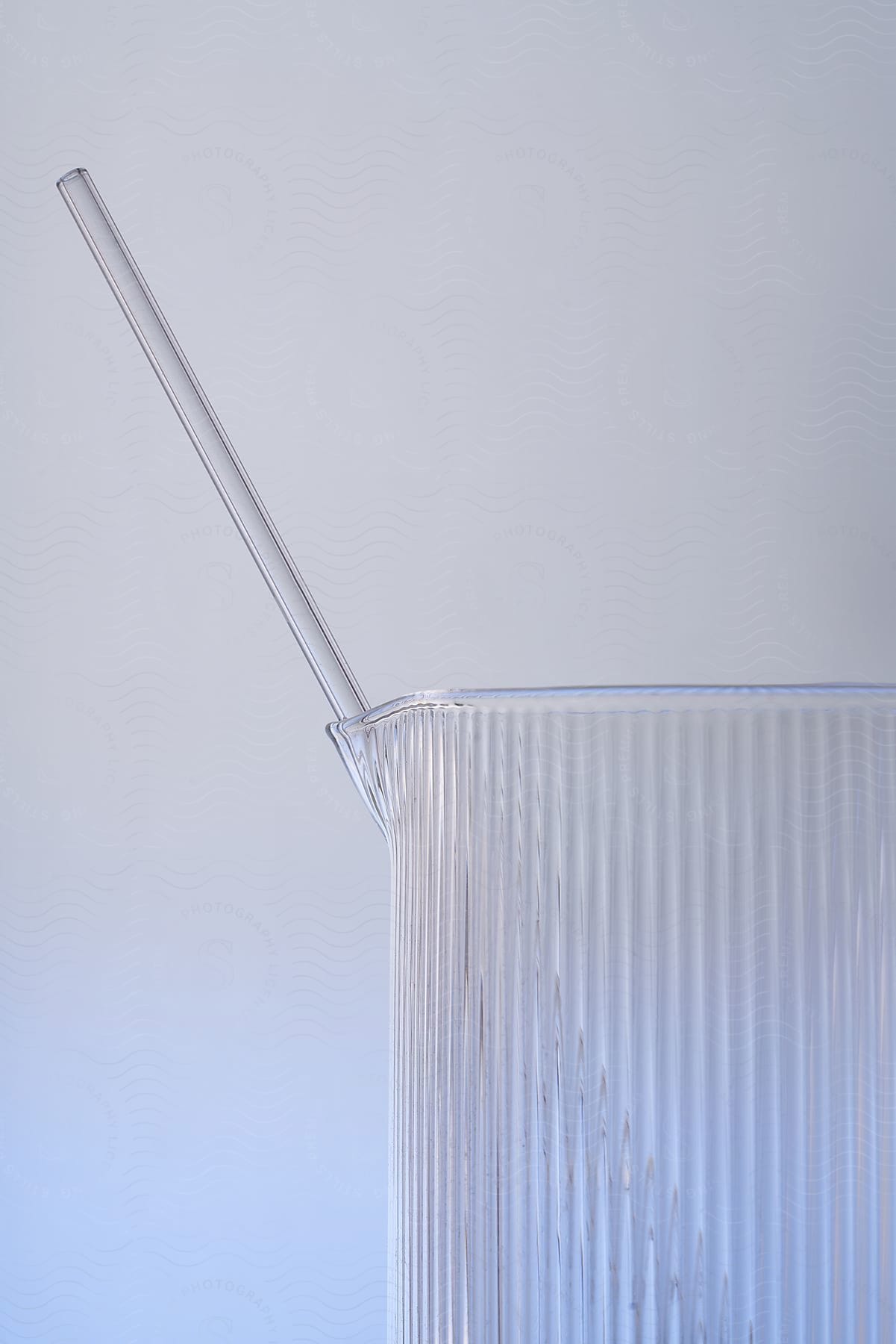 Transparent cup with vertical grooves and a transparent straw inside the cup.