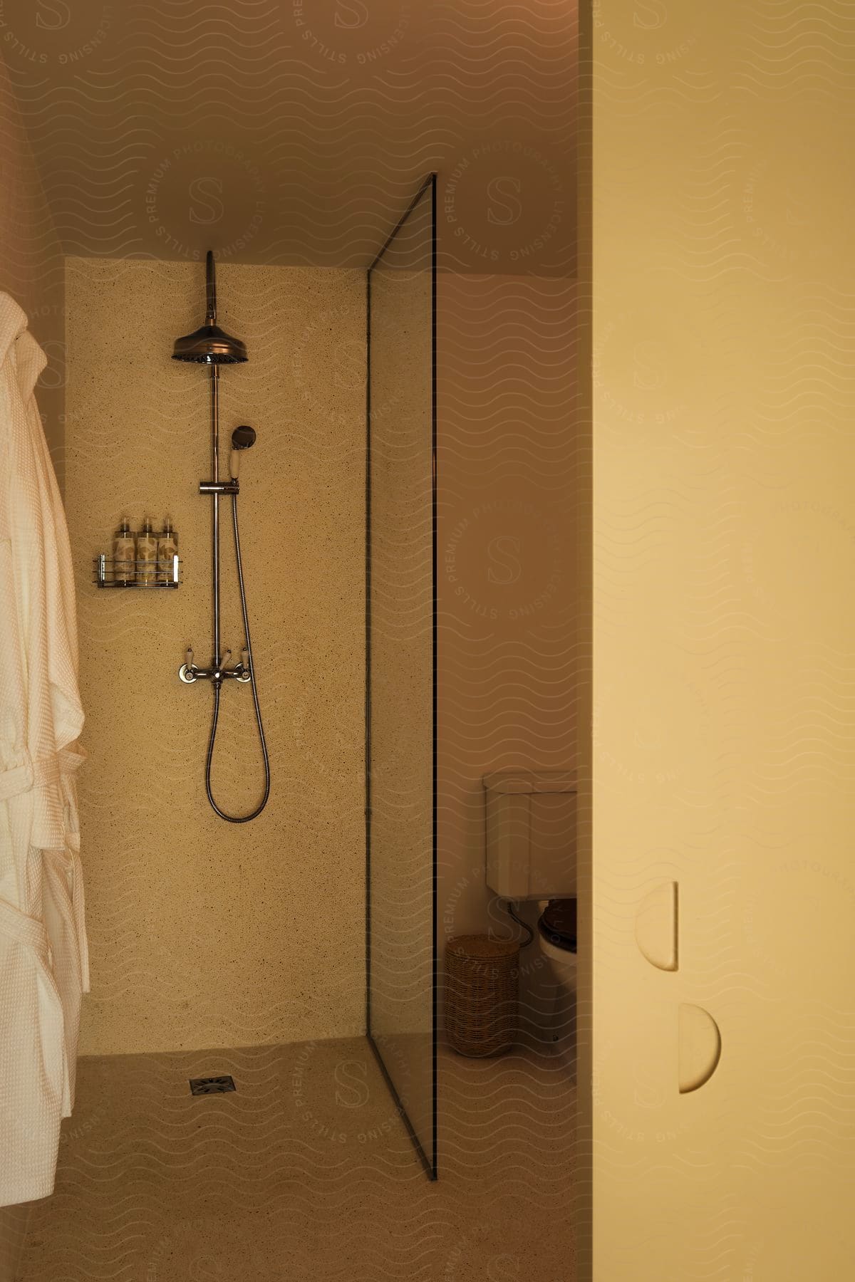 Interior design of a bathroom stall with shower and a bathrobe on the wall