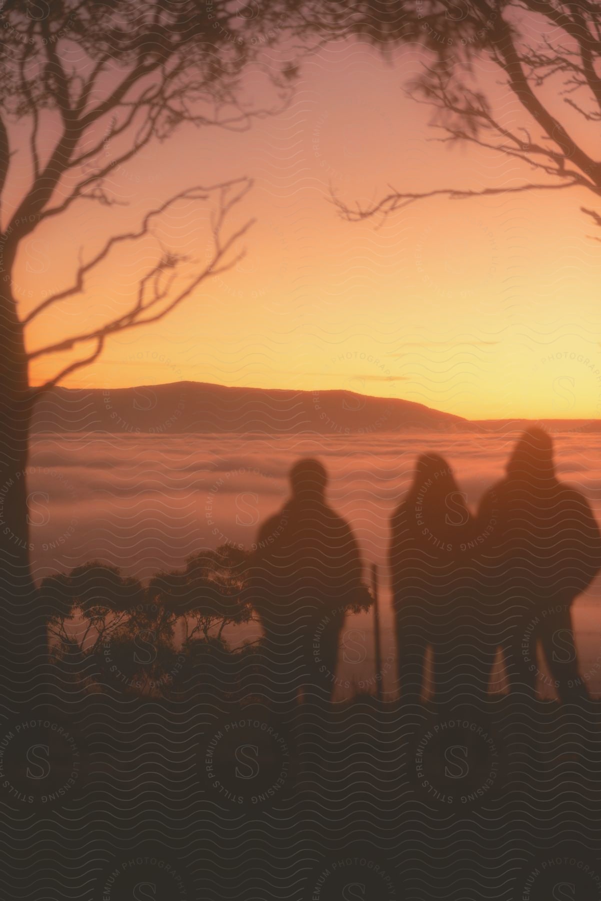 Three people looking on to a hill in the distance, the clouds covering it's way