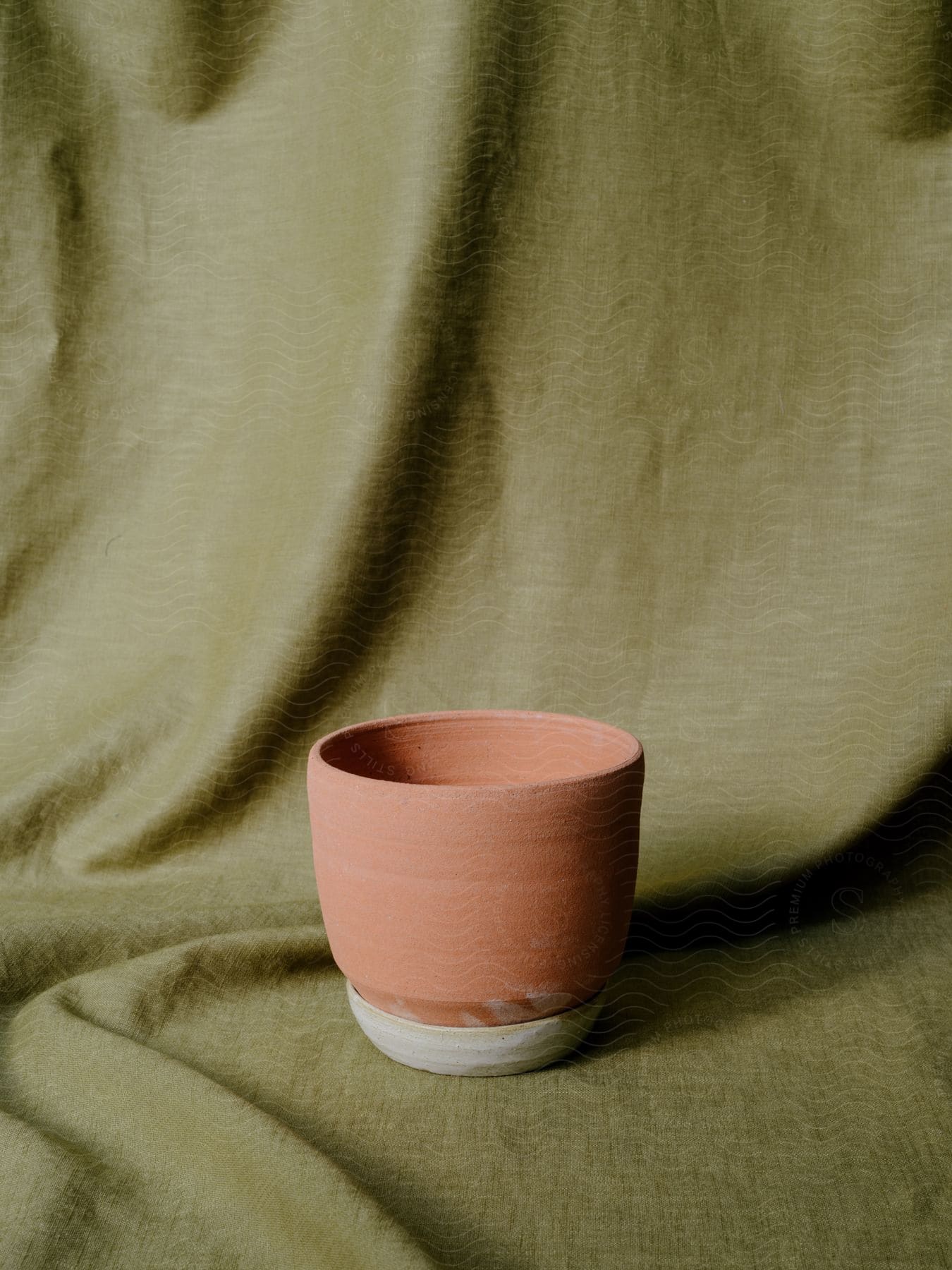 A pink clay pottery bowl on a beige cloth