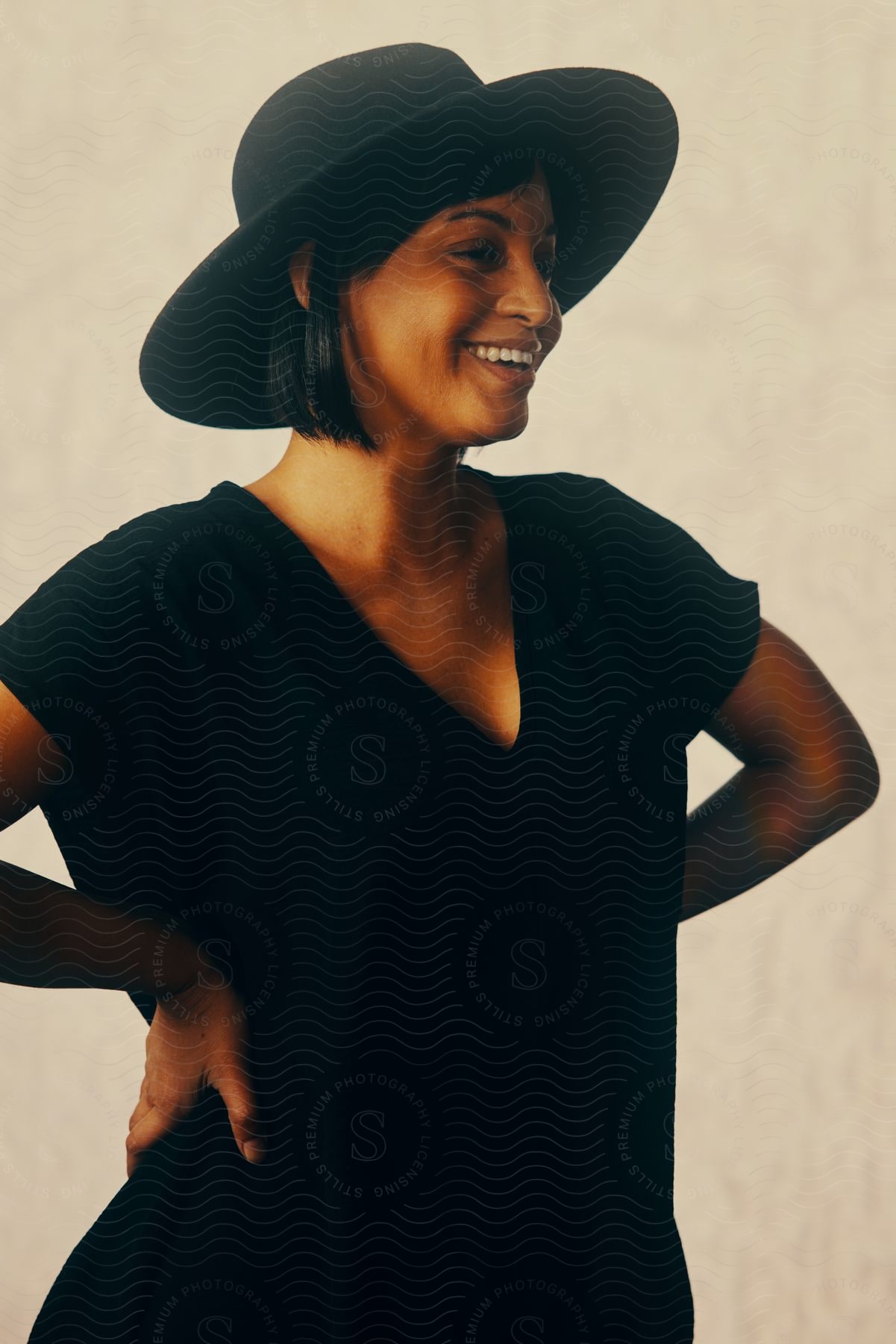 Smiling woman in black hat and clothes poses against a white background