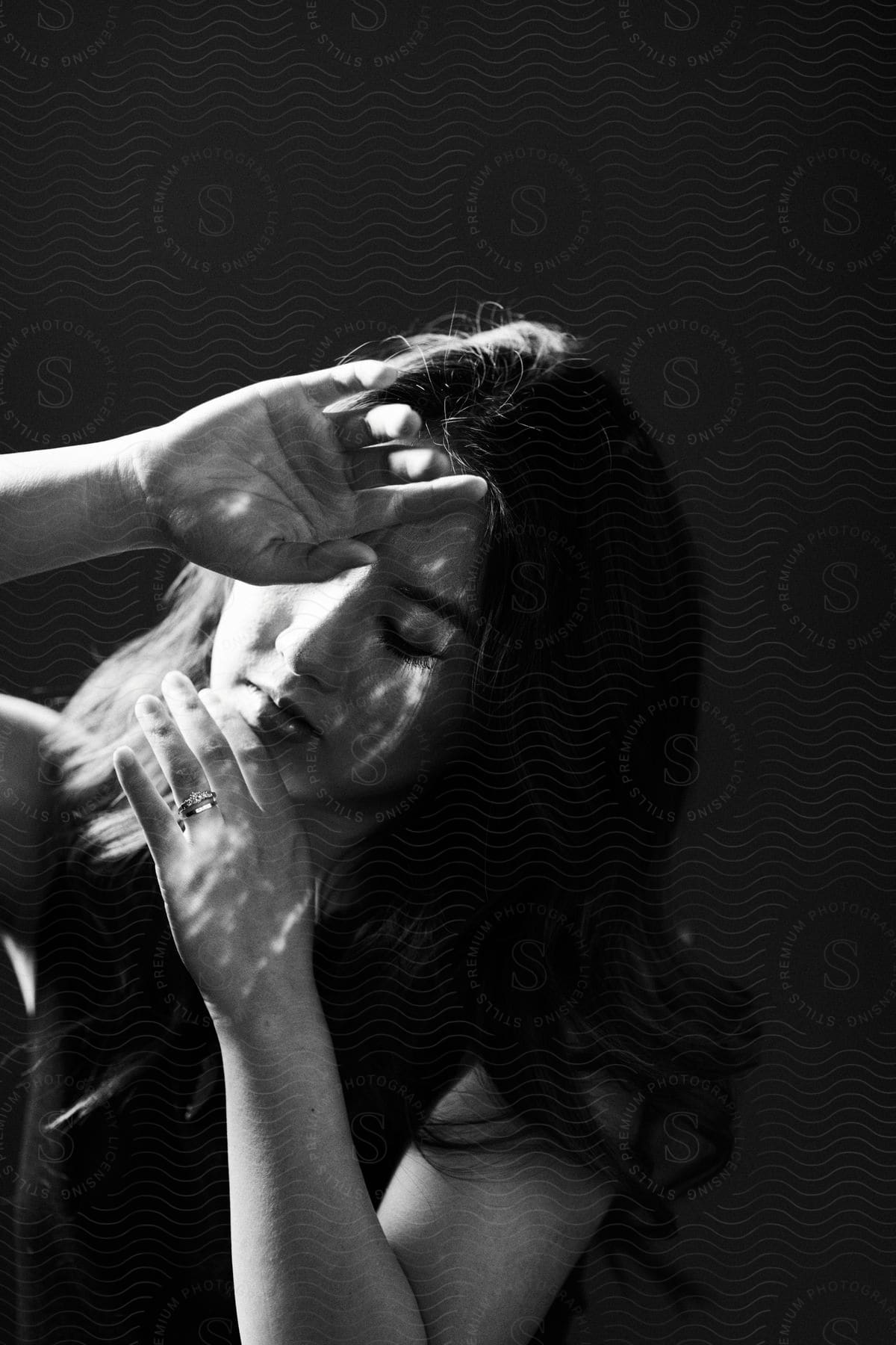 A woman with her eyes closed and hands in front of her face as if blocking out the sun