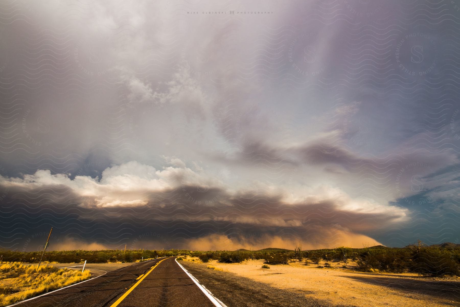 A dust storm moves over the land at the end of a freeway in the desert