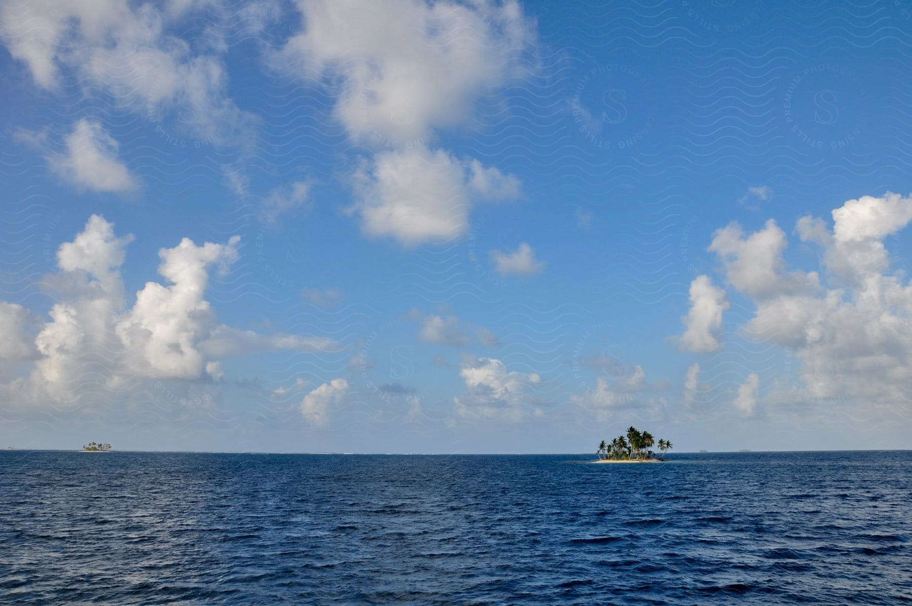 Trees on small islands in the open sea under a blue cloudy sky