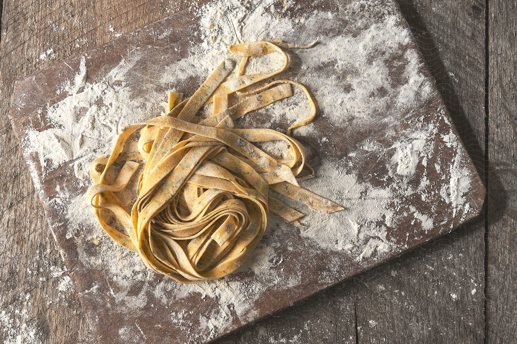 Closeup of homemade noodles on a floured cutting board on a wooden table top