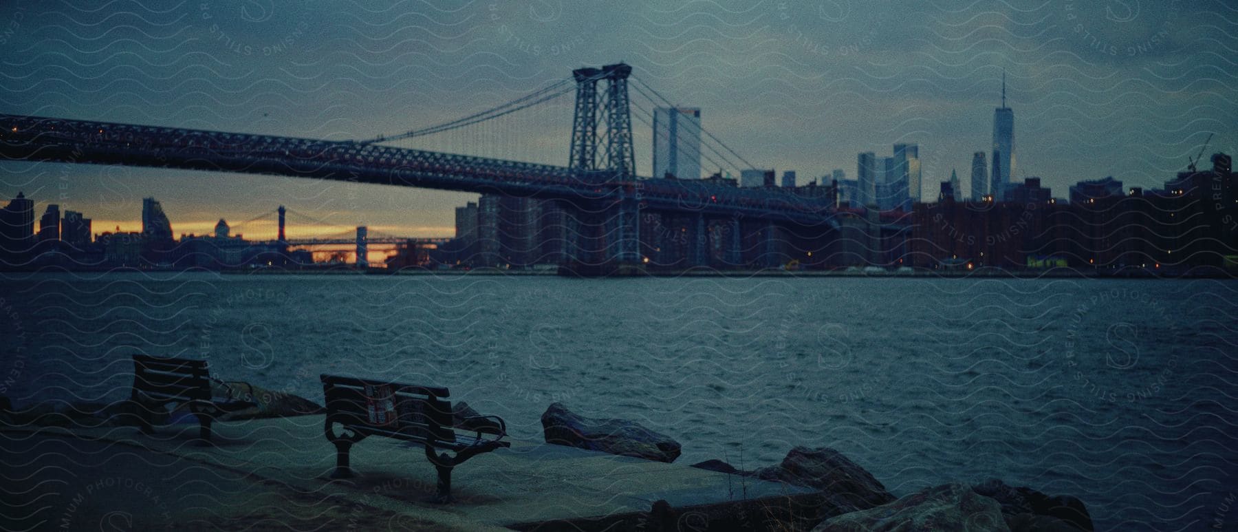 Landscape of williamsburg bridge over river and high rise buildings in the background at dusk