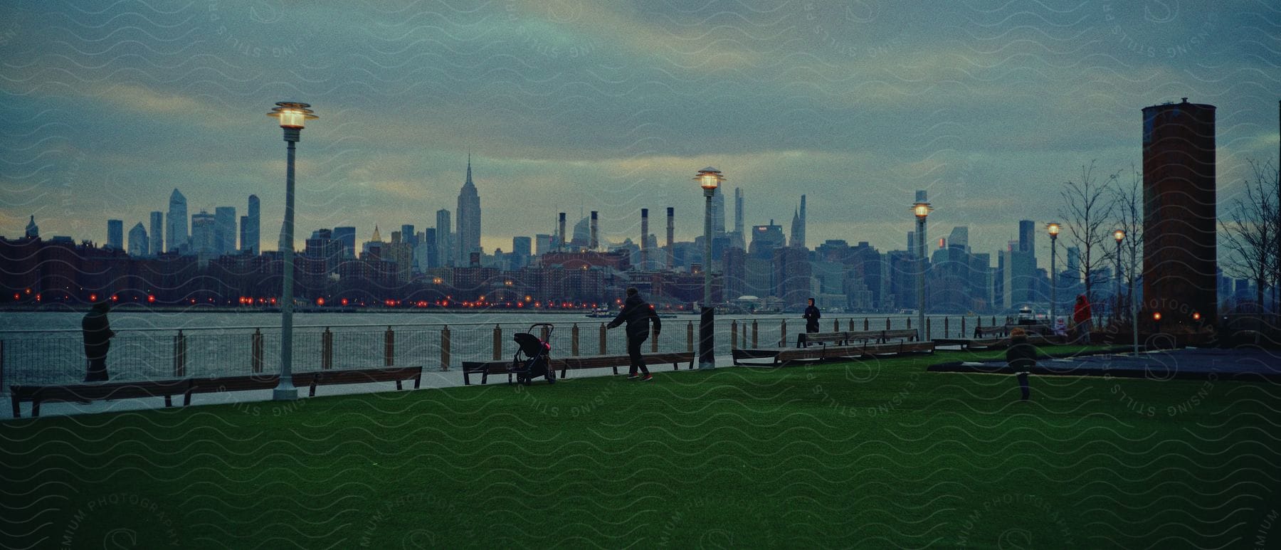 People sitting and walking near the shoreline overlooking the city skyline