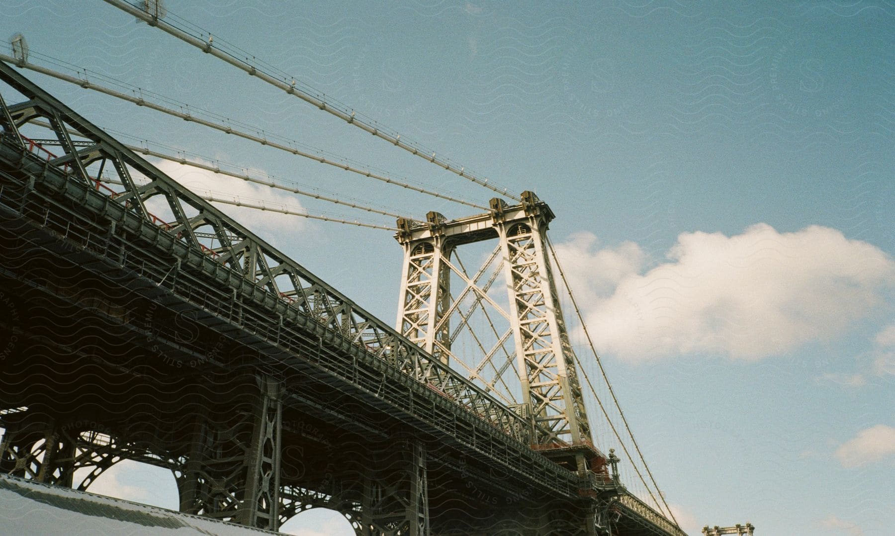 A large bridge for cars and pedestrians in new york against a blue sky with clouds