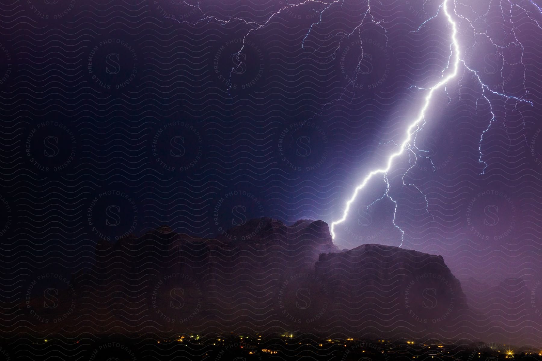 Giant peaks flash in the dark with bolts of lightning in a mountainous landscape