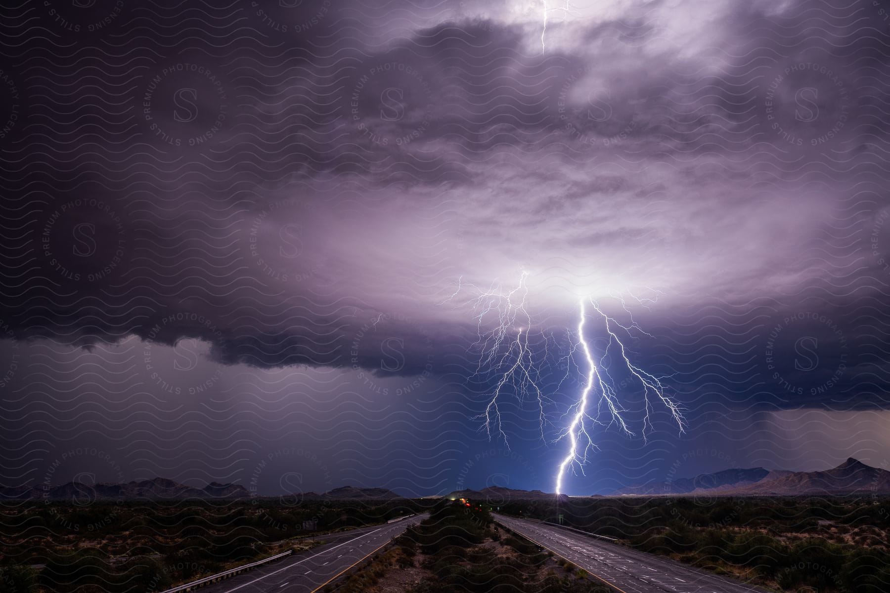 A lightning bolt emerges from a dark cloud in the background against the backdrop of a highway