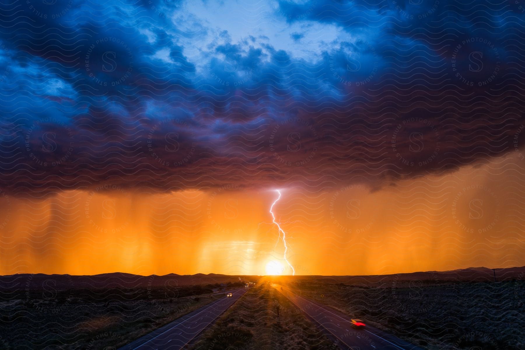 Lightning strikes on a dark highway with a sunset and stormy clouds in the background