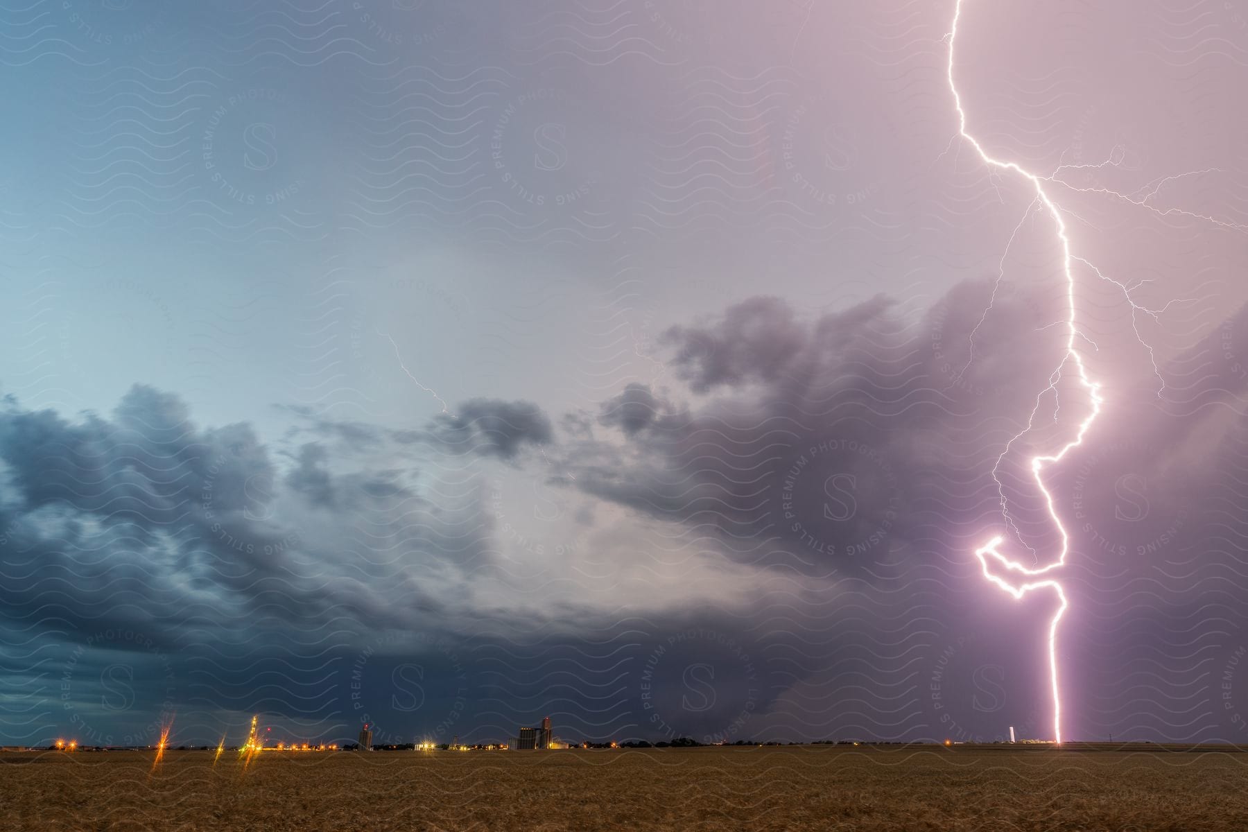 Lightning and rain falling from storm clouds over a small town in the plains