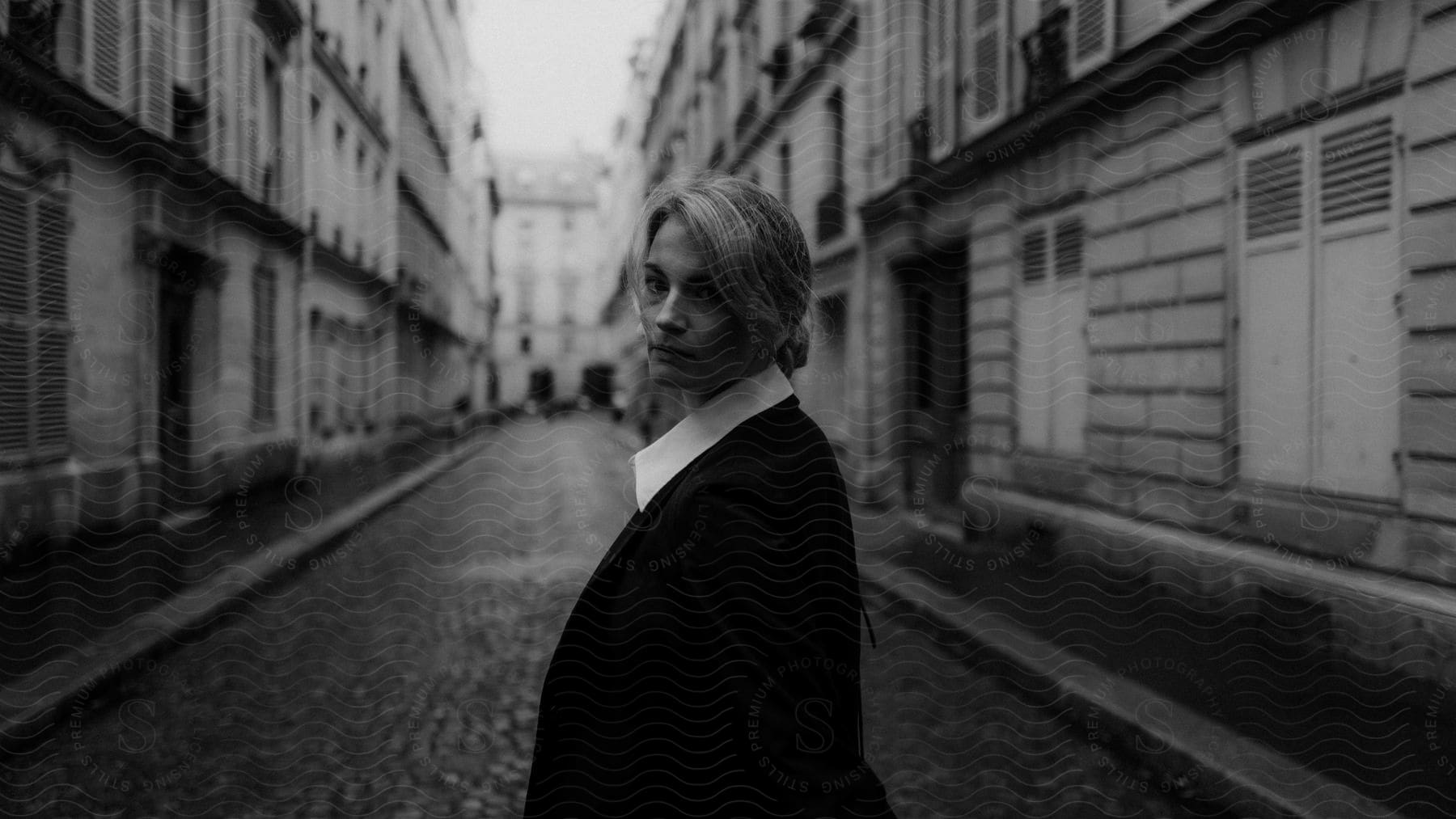 Blonde woman in black suit standing in a european street