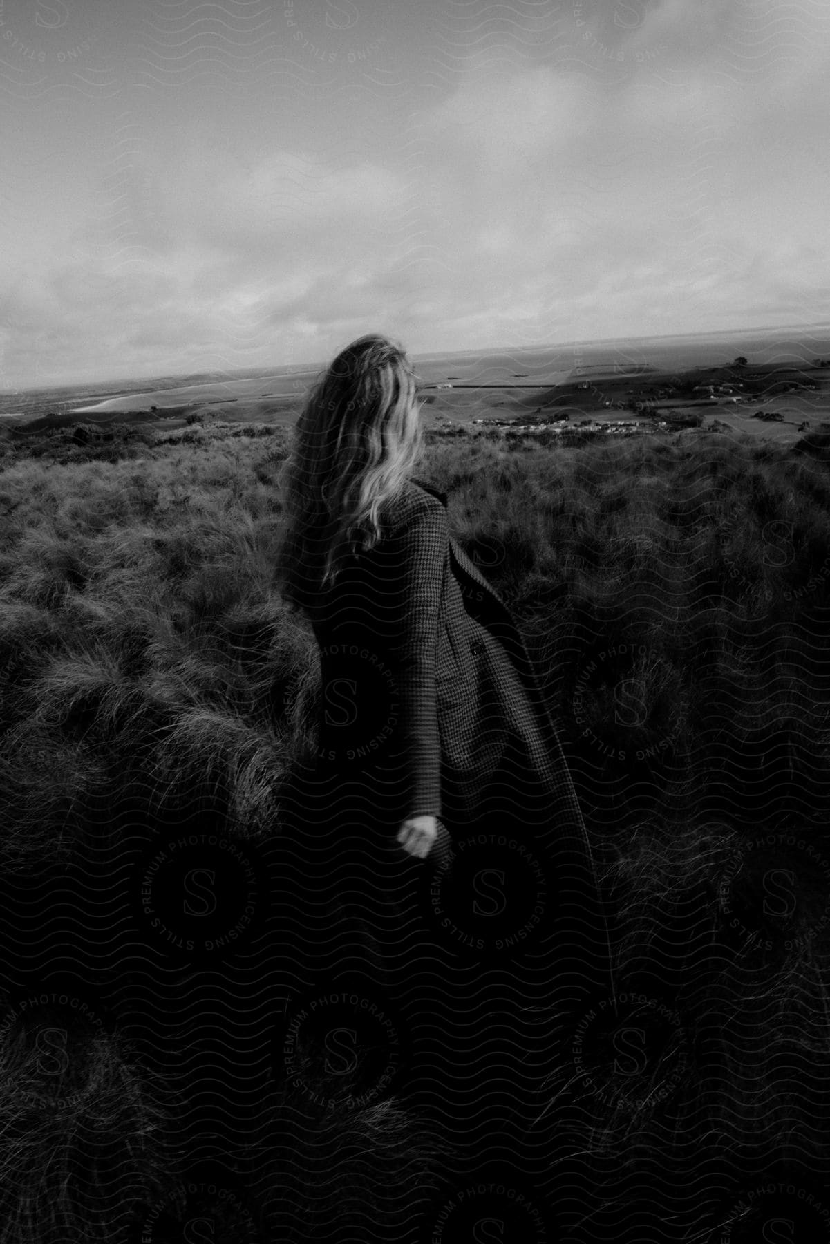 Woman standing outdoors and looking at the horizon in black and white