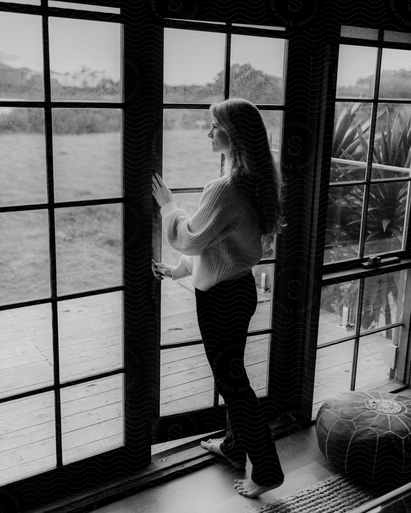 A woman opens a door with large glass windows to the backyard of a house
