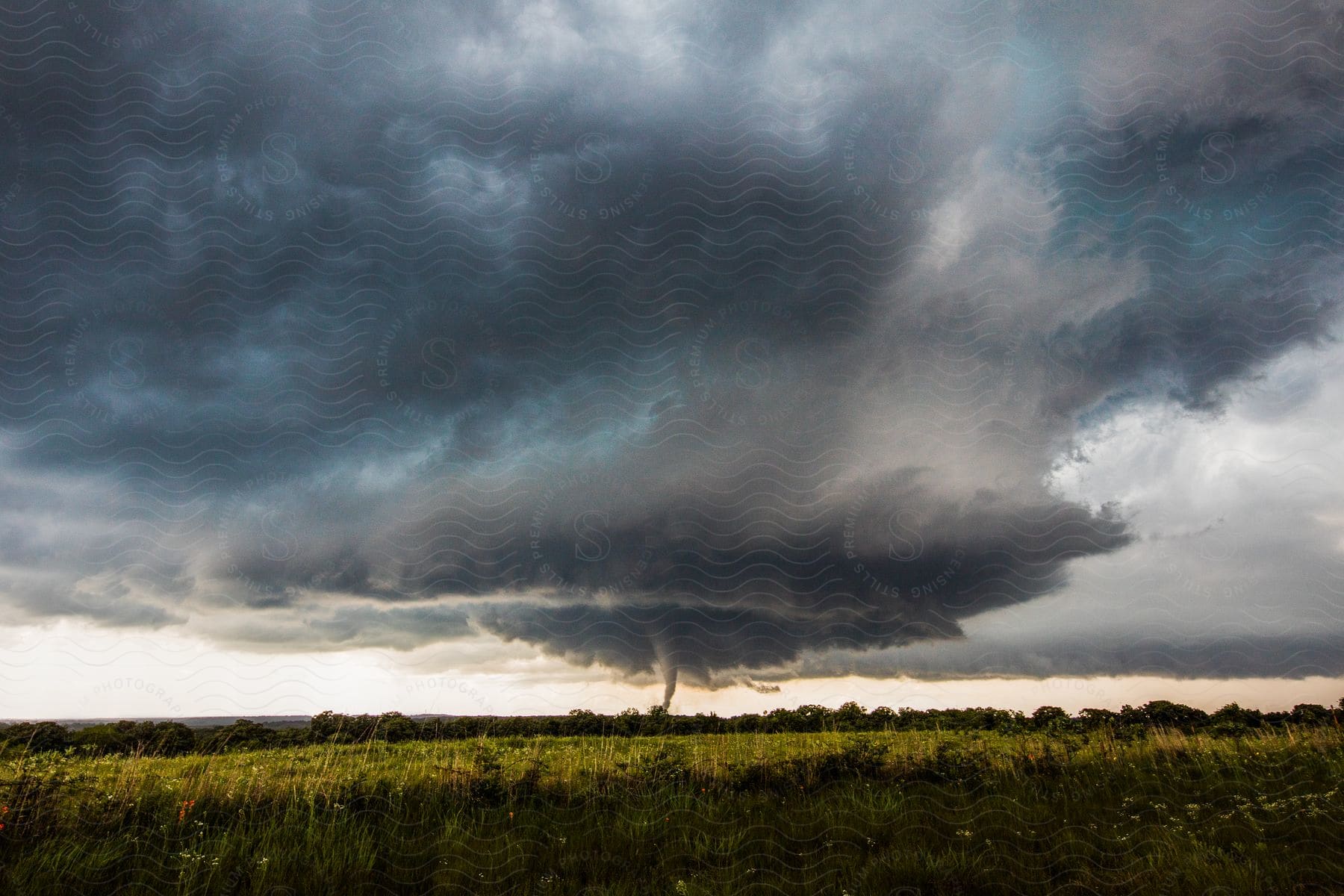 Incoming storm with tornado touching down amidst the once serene blue sky causing chaos