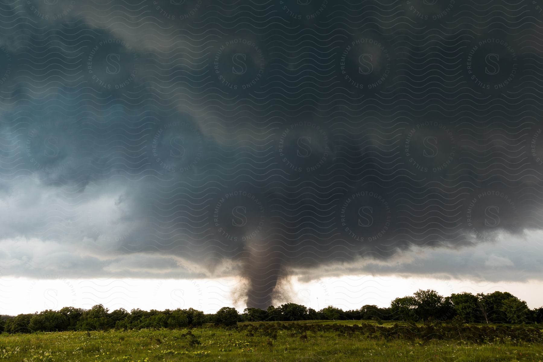 Tornado seen in the distance on a green meadow grey sky in katie and wynnewood oklahoma