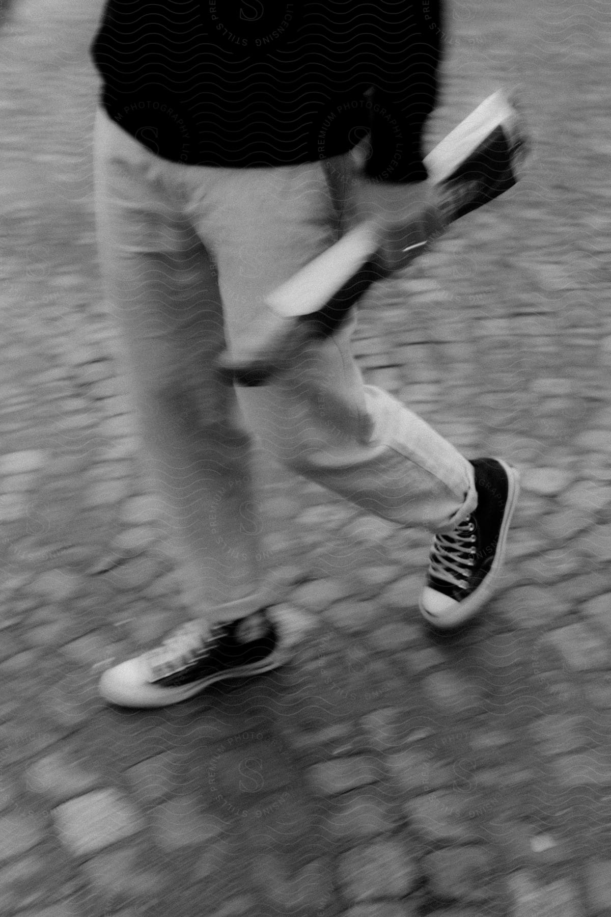 A person wearing sneakers walks on cobblestone