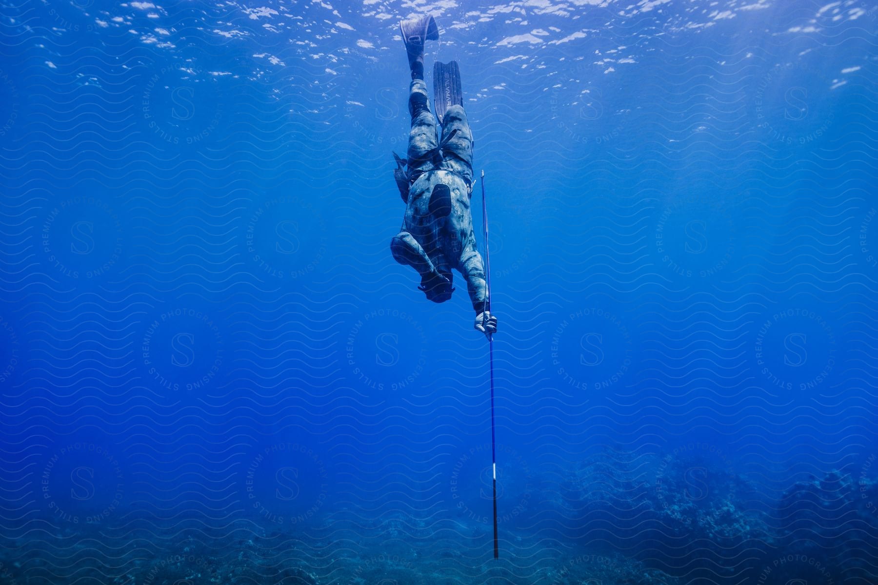 A person diving to the bottom of the bright blue sea with flippers on