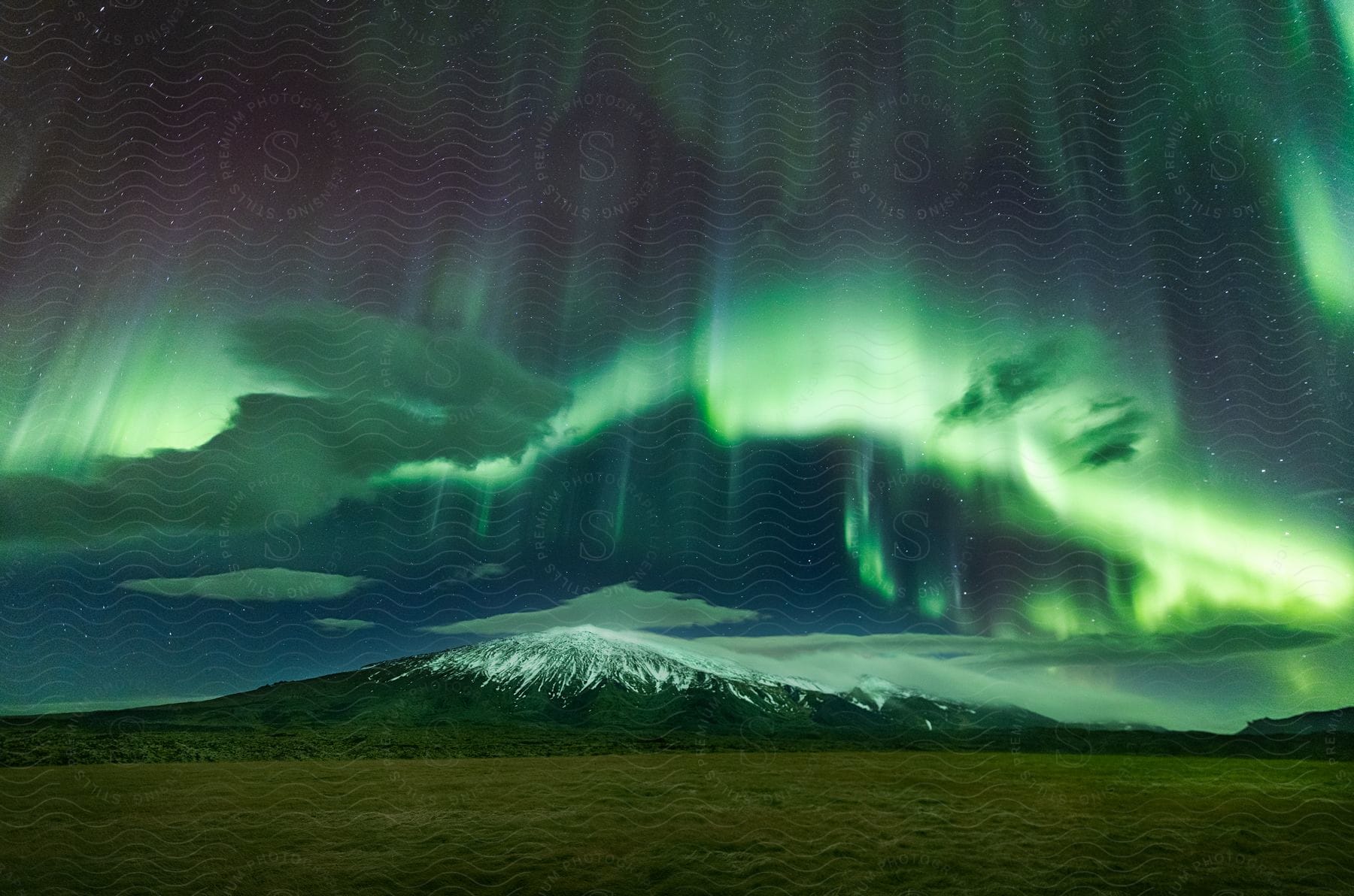 Aurora borealis lights stretch over snowcovered mountain under starry night sky