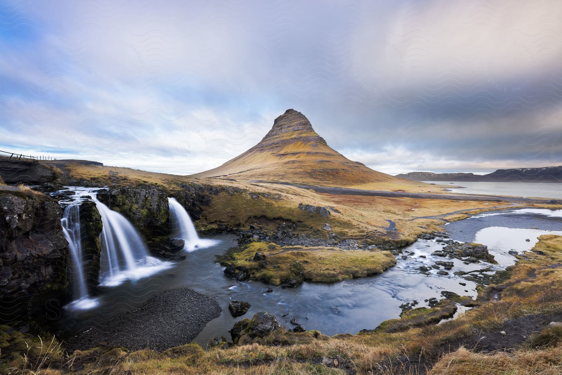 A landscape shot of a small waterfall on a river in front of a rocky peak