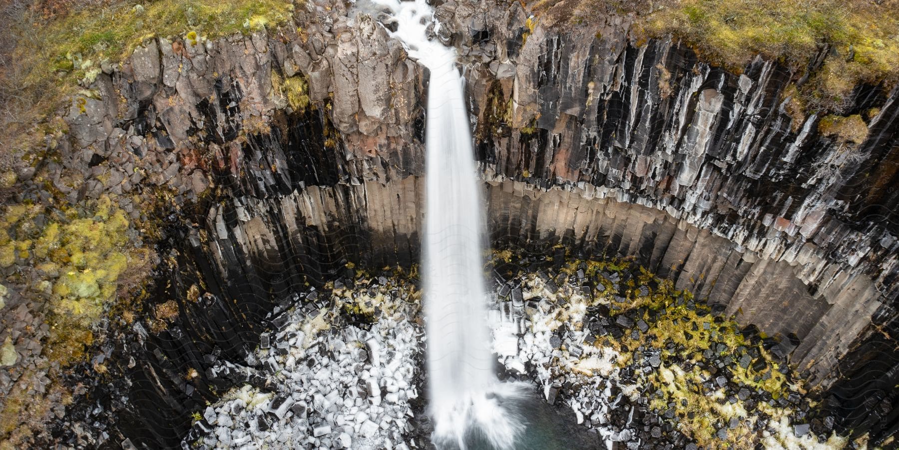 A Narrow Waterfall Over A Cliff In Iceland