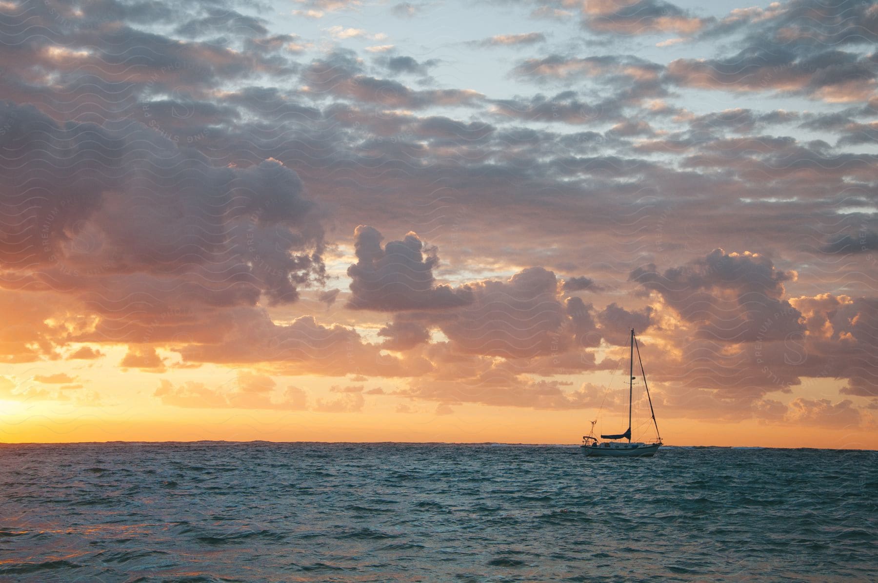 A lone boat sails on the open sea at dawn