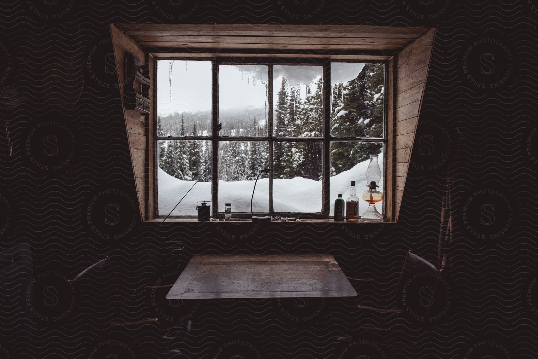 Dark interior of a house with a snowcovered forest visible through a window