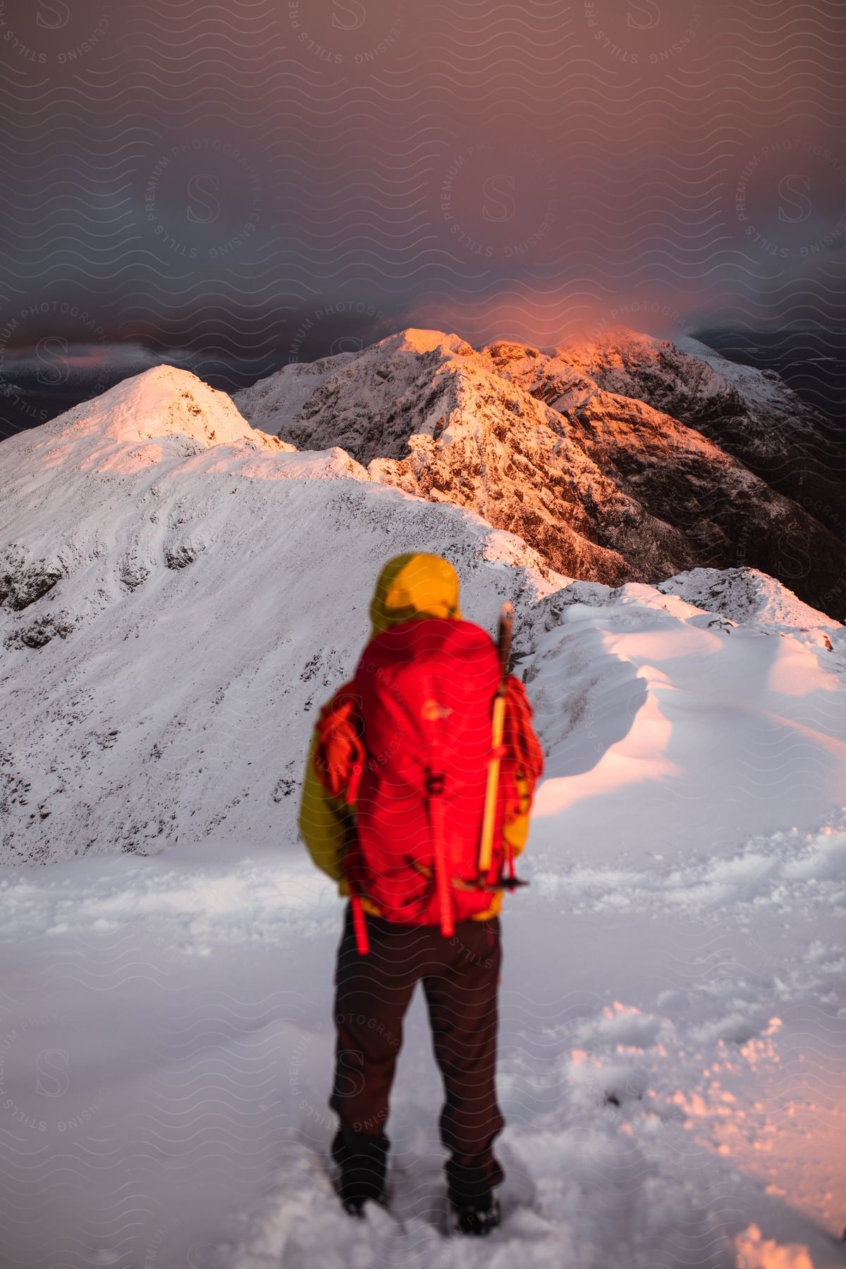 A hiker follows footprints along a snowy ridge in the scottish mountains