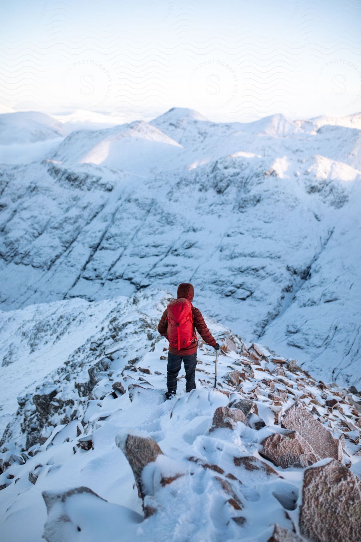 A hiker wearing a backpack hikes across a snowcovered mountain ridge in scotland during winter