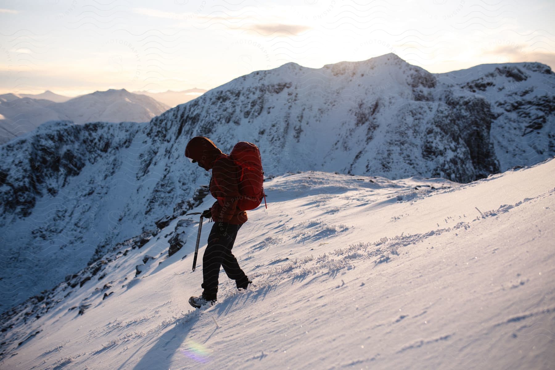 A hiker walks down a snowy slope on top of a mountain