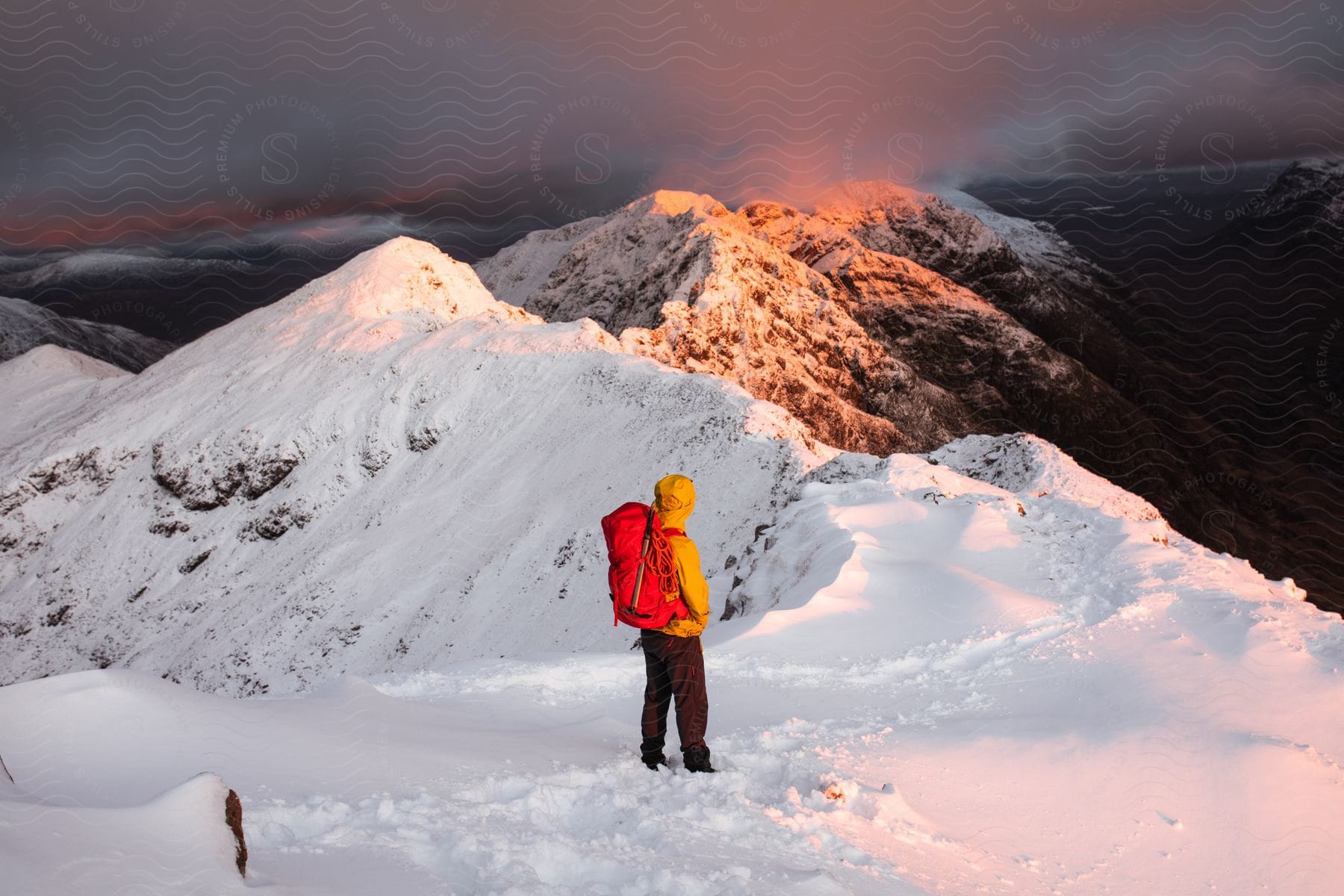 A hiker with a backpack walking on a snowcovered mountain ridge with distant mountains