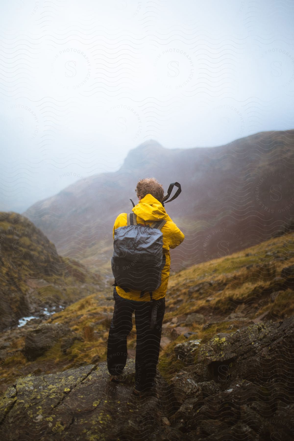 A man on a mountain photographing the landscape in front of him