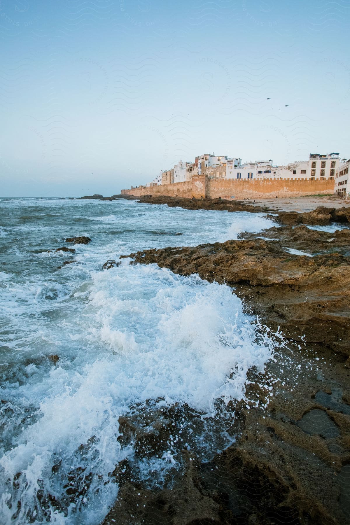 Water and rocks meeting at the shoreline near a walled city