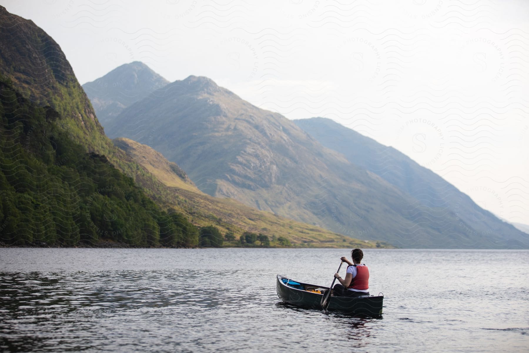 A Man Canoeing On A River Near Mountains