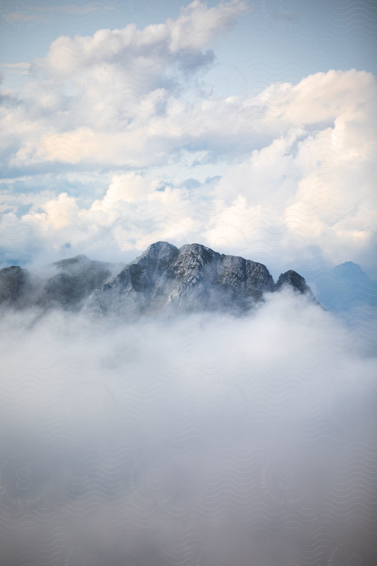 A natural landscape with a mountain surrounded by clouds